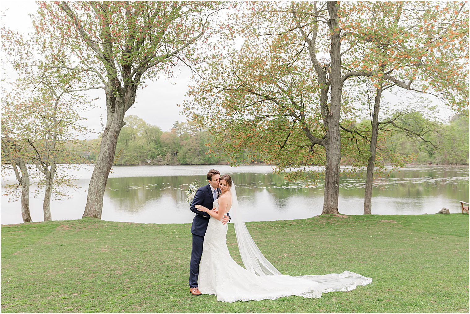 bride and groom kiss by lake outside Indian Trail Club