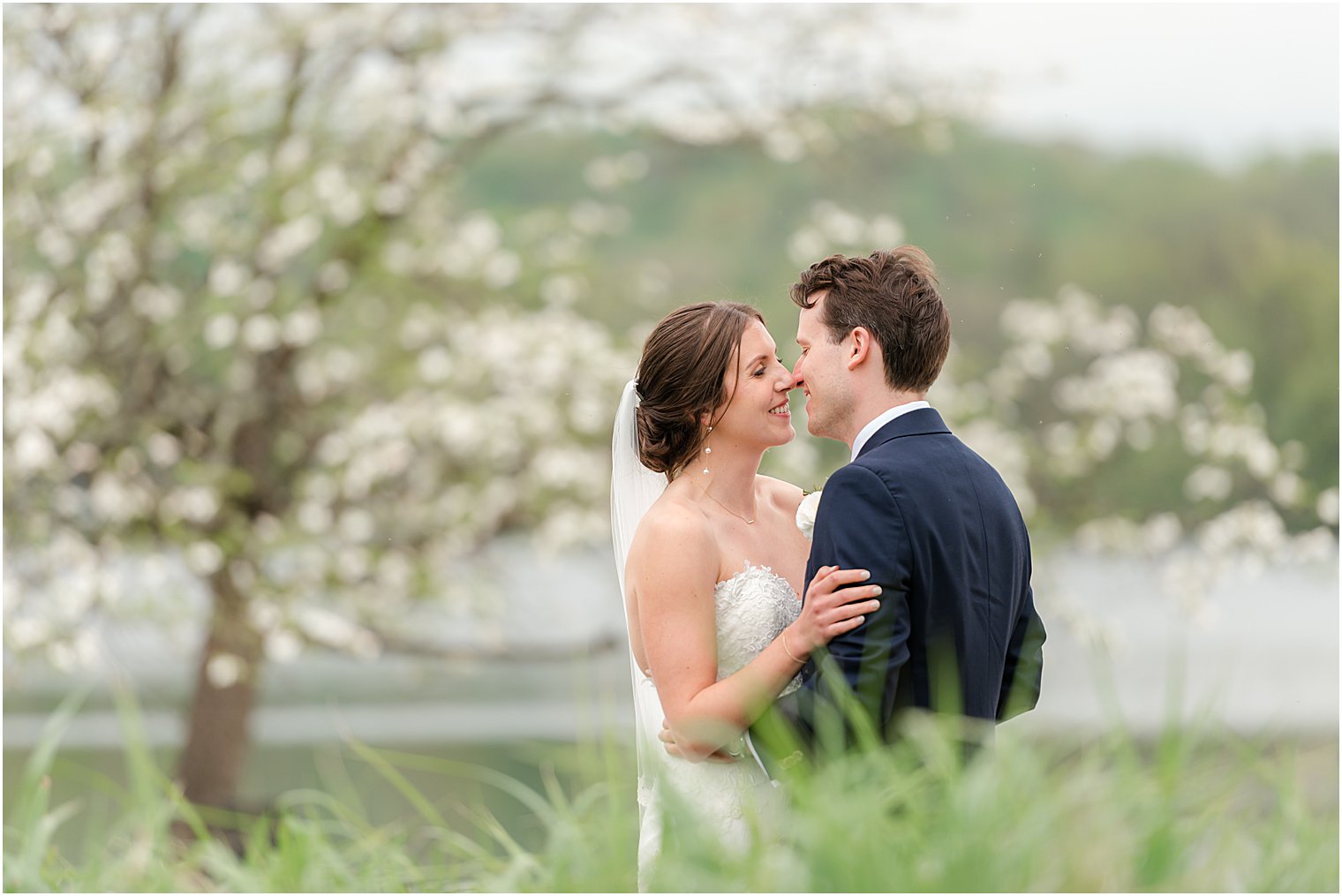 bride and groom kiss behind bush by lake at the Indian Trail Club