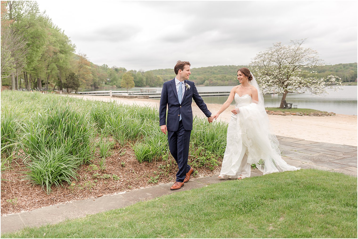 bride and groom hold hands walking along path at Indian Trail Club