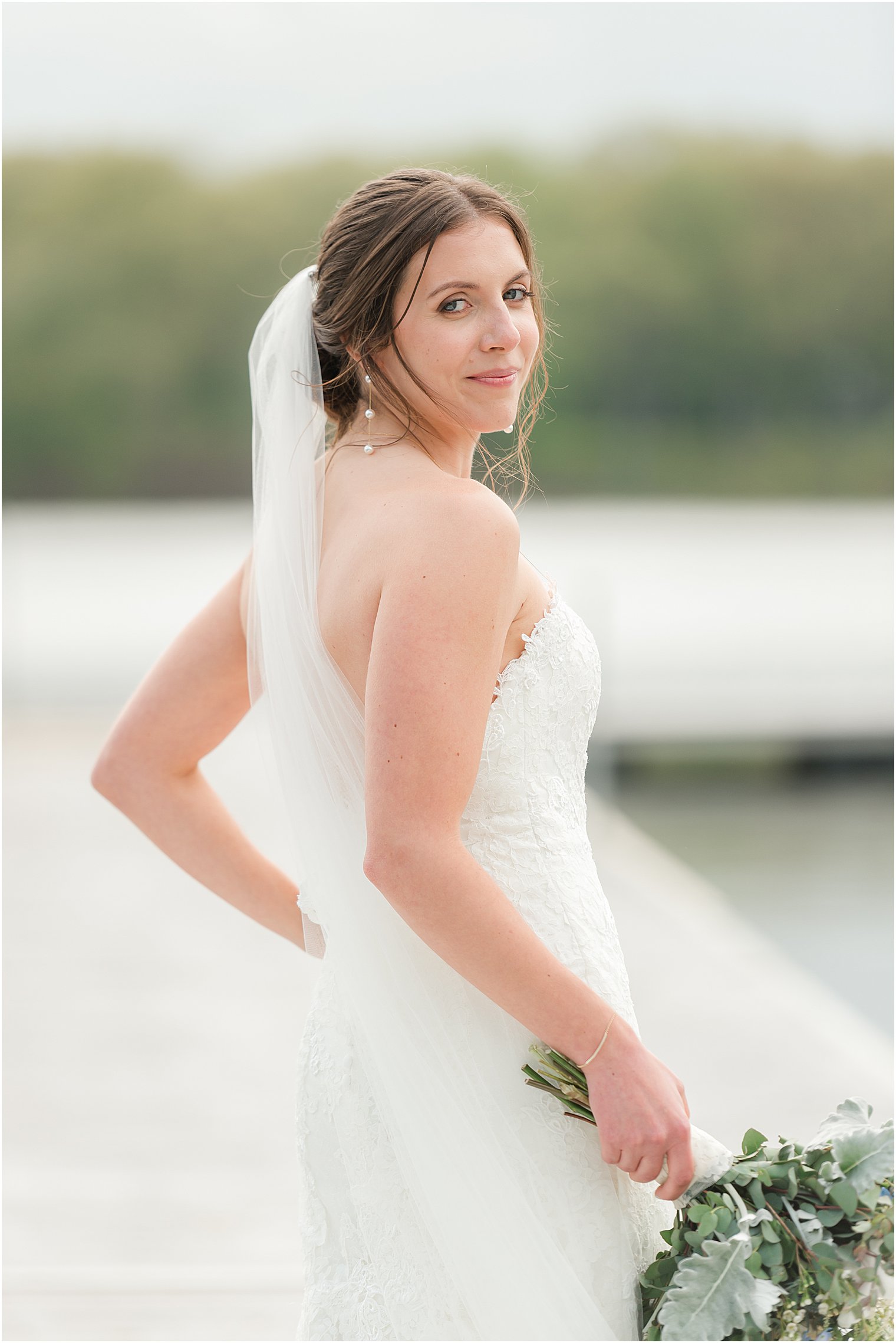 bride walks holding bouquet on dock at Indian Trail Club