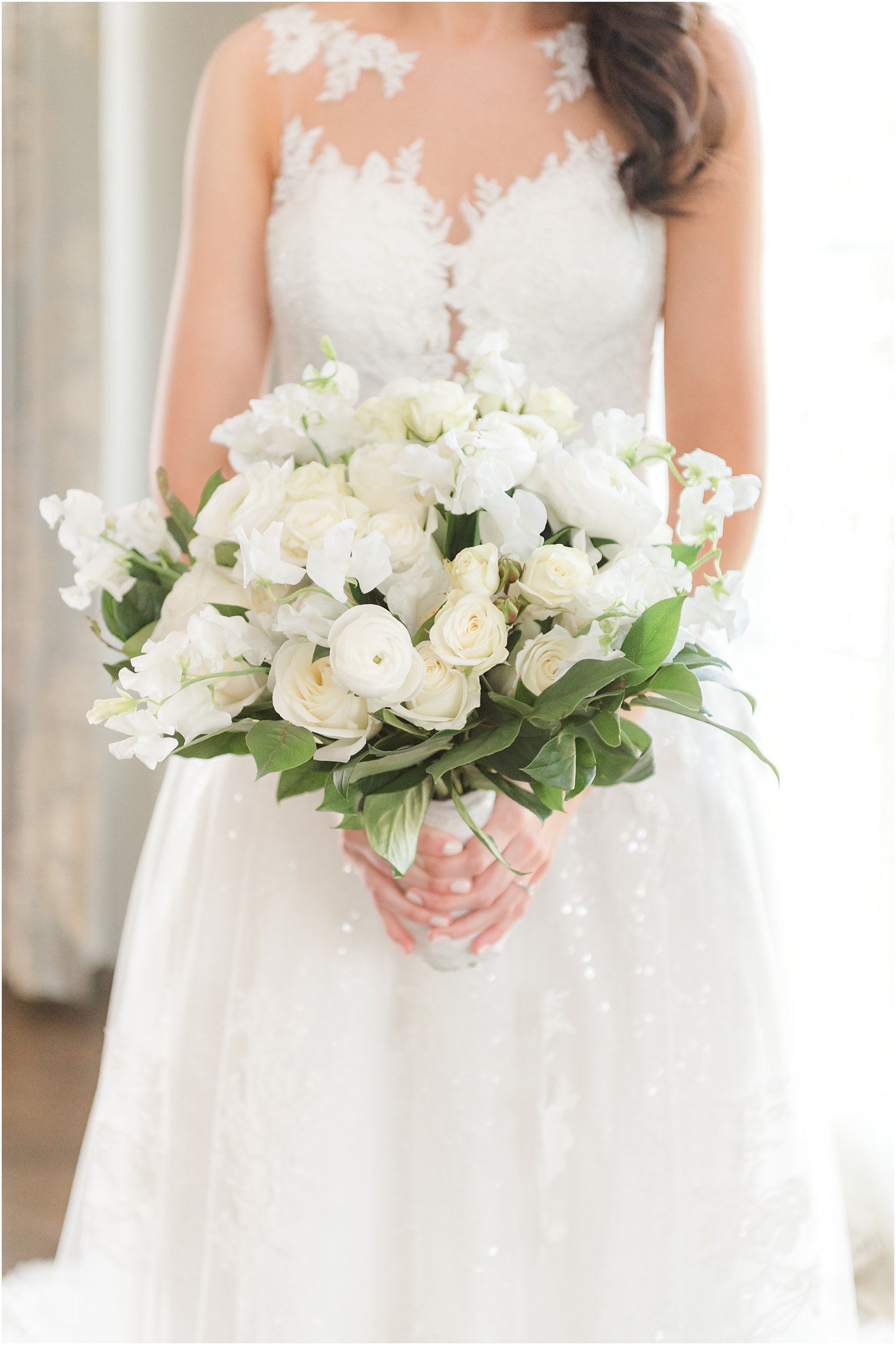 bride holds bouquet of all white flowers