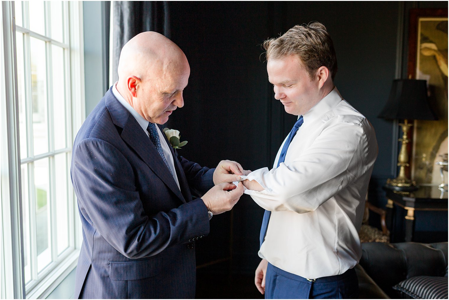 dad helps son with cufflinks on wedding day