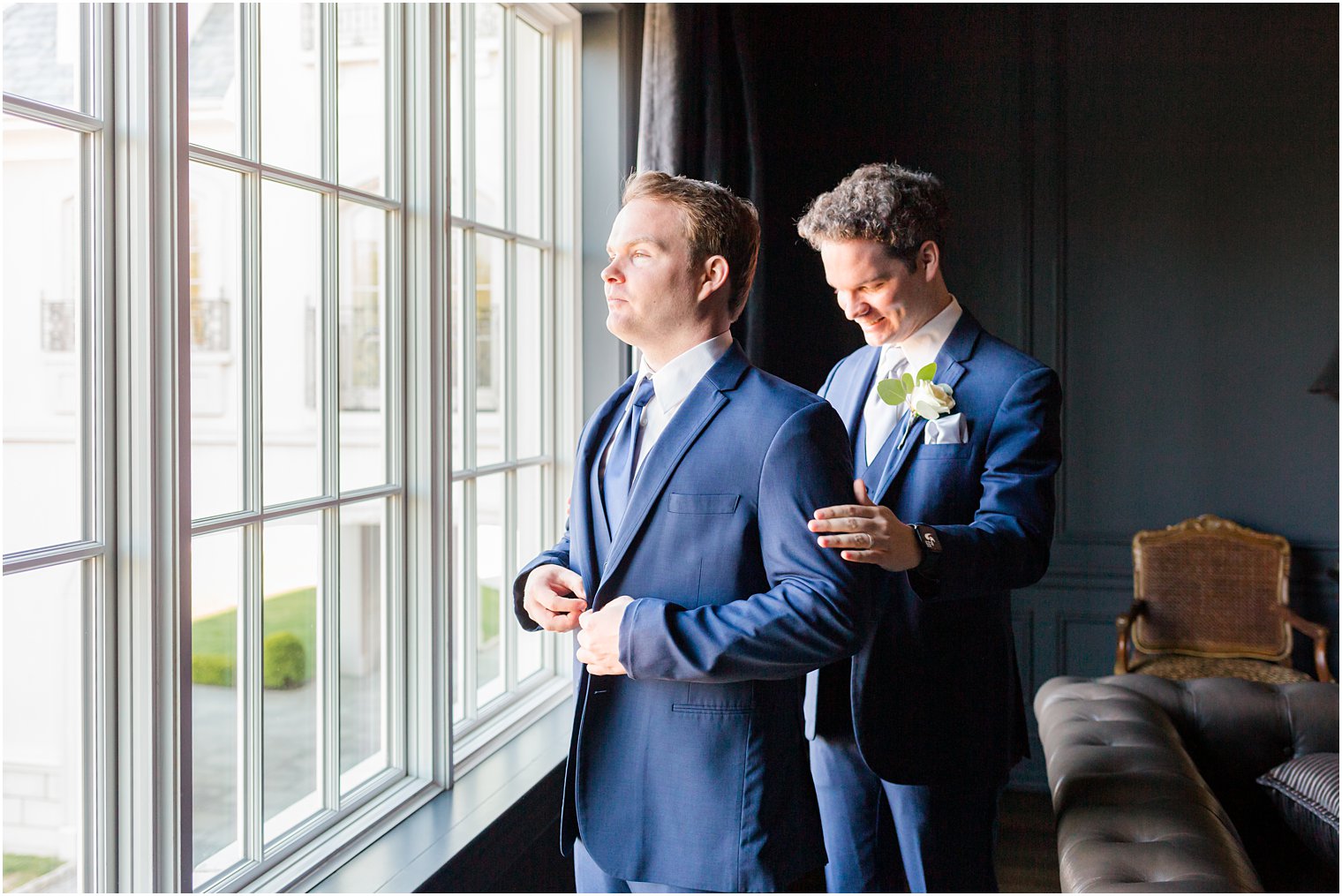 groomsman helps brother into blue jacket