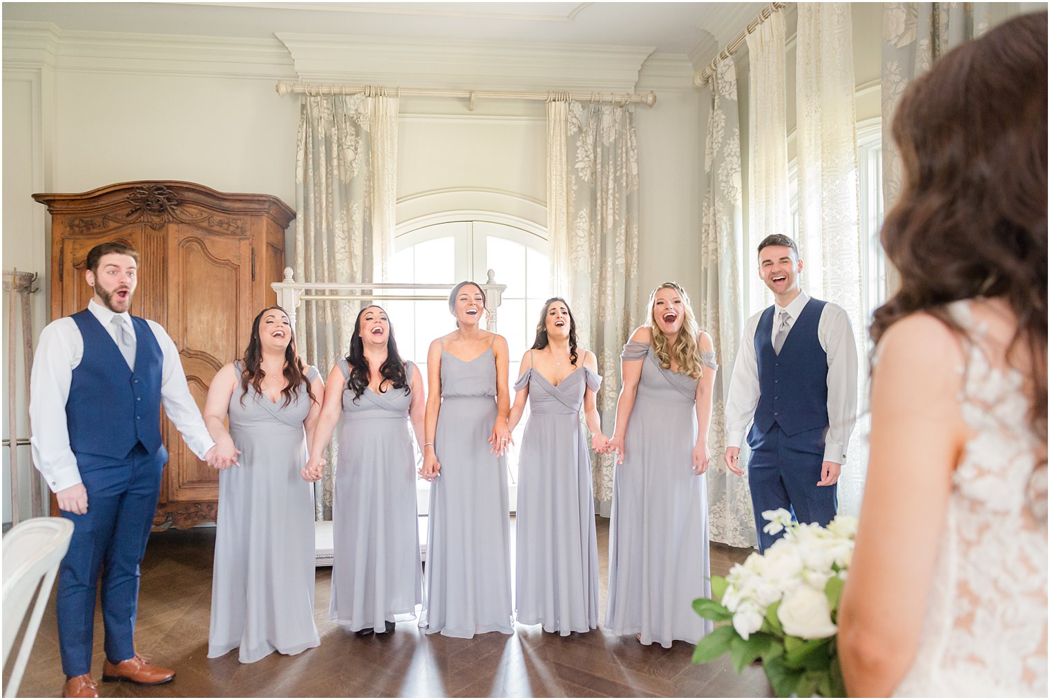 bridal party reacts to bride in wedding gown