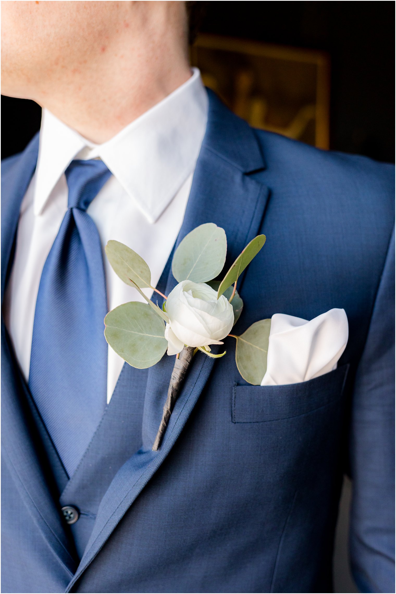 groom stand in blue suite with white boutineere 