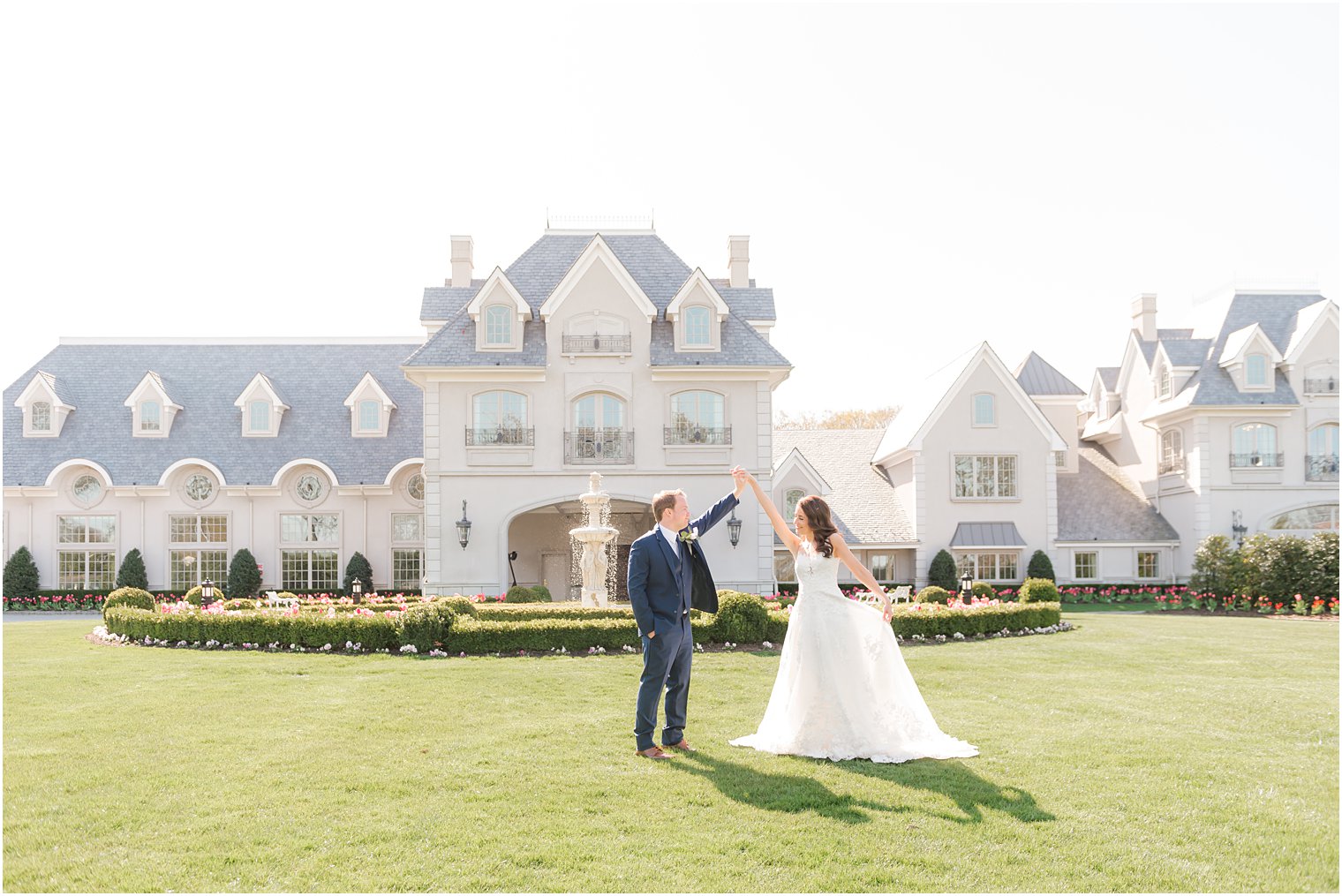 groom twirls bride on lawn of Park Chateau Estate on wedding day