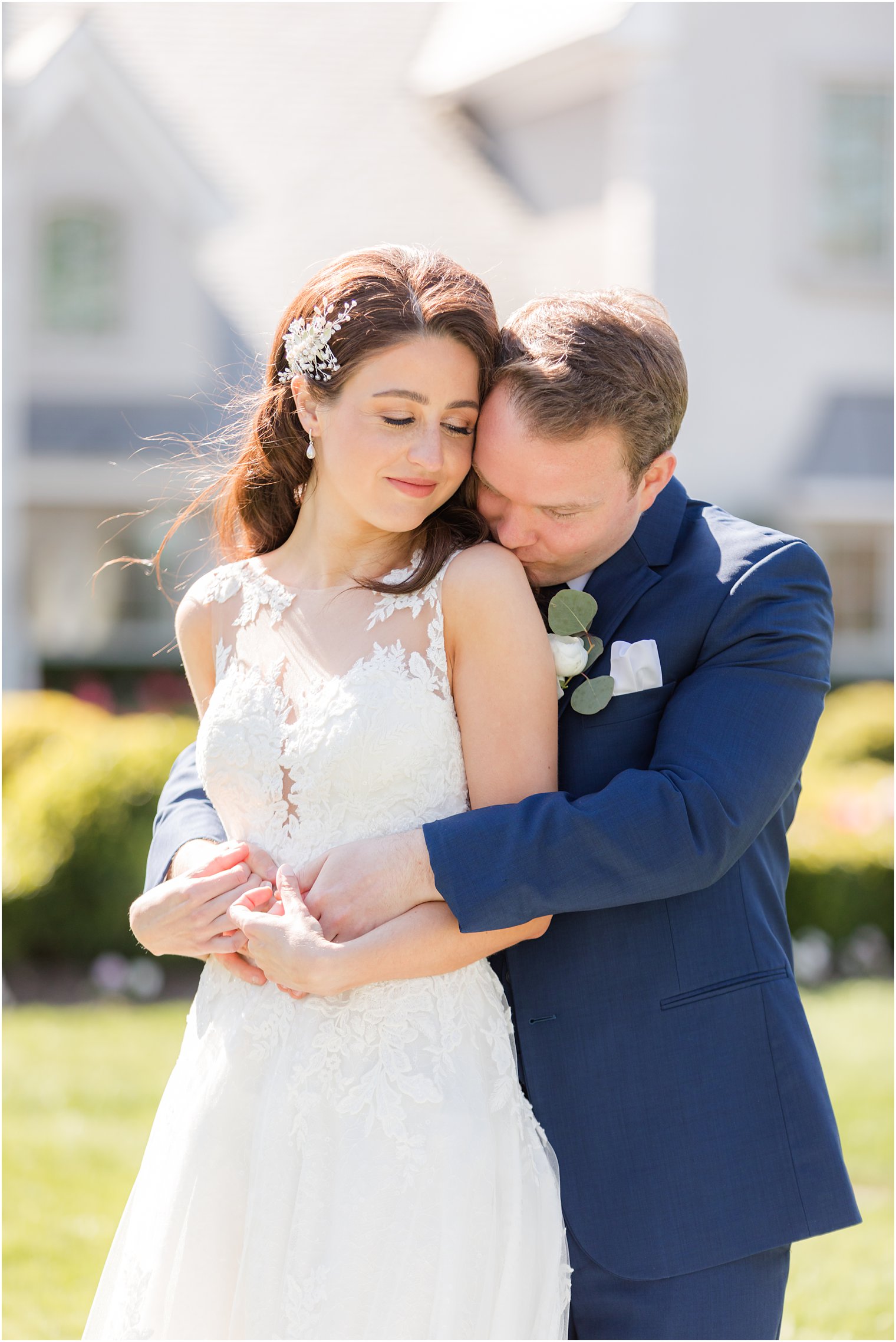 groom hugs bride and kisses her shoulder during Park Chateau Estate wedding photos