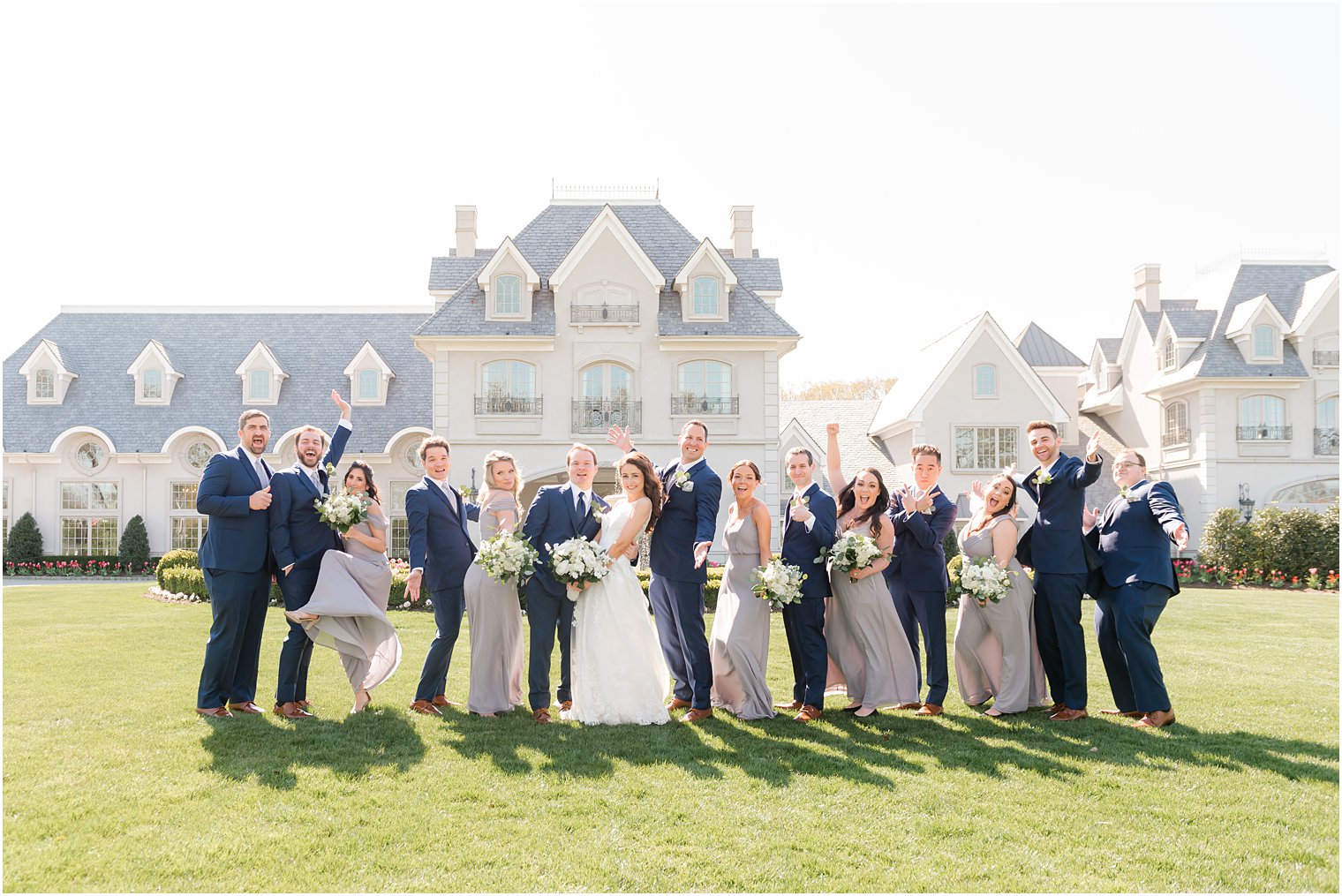 couple kisses while bridal party cheers on lawn of Park Chateau Estate
