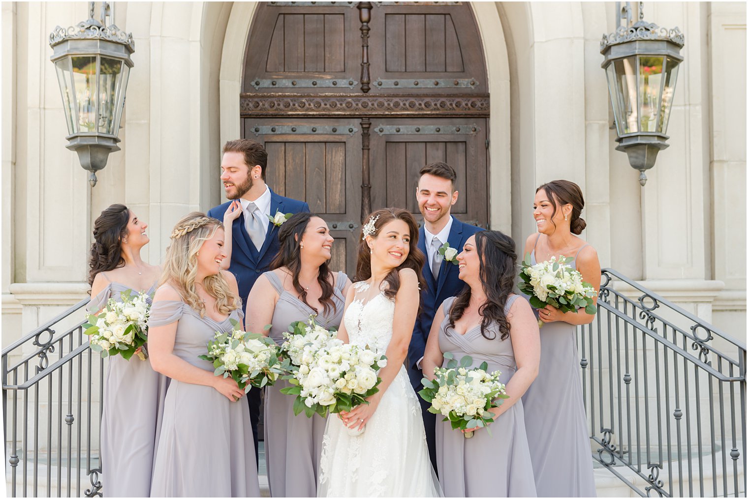 bride smiles with bridal party around her on steps of chapel in NJ