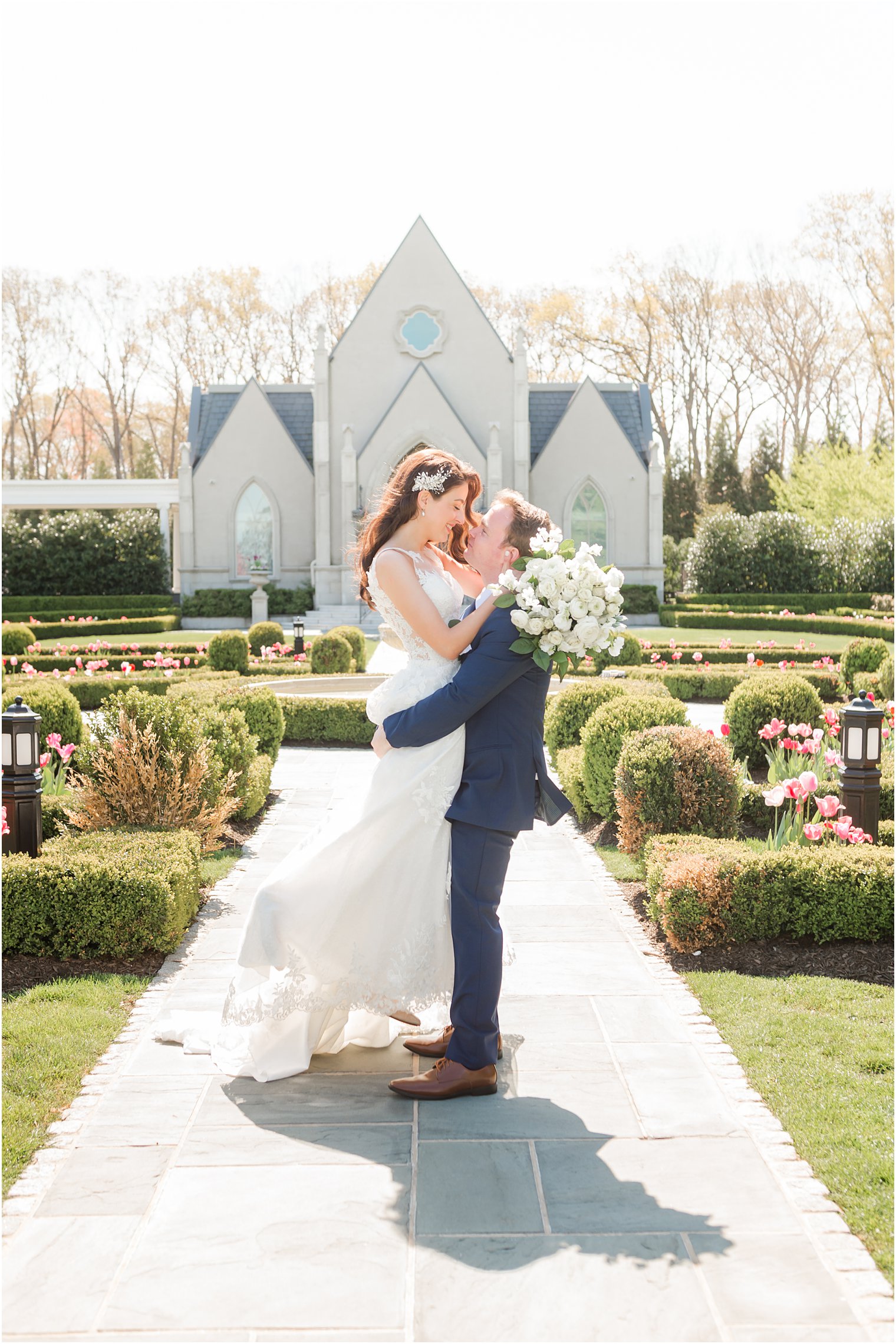 groom lifts bride during spring wedding portraits in New Jersey garden
