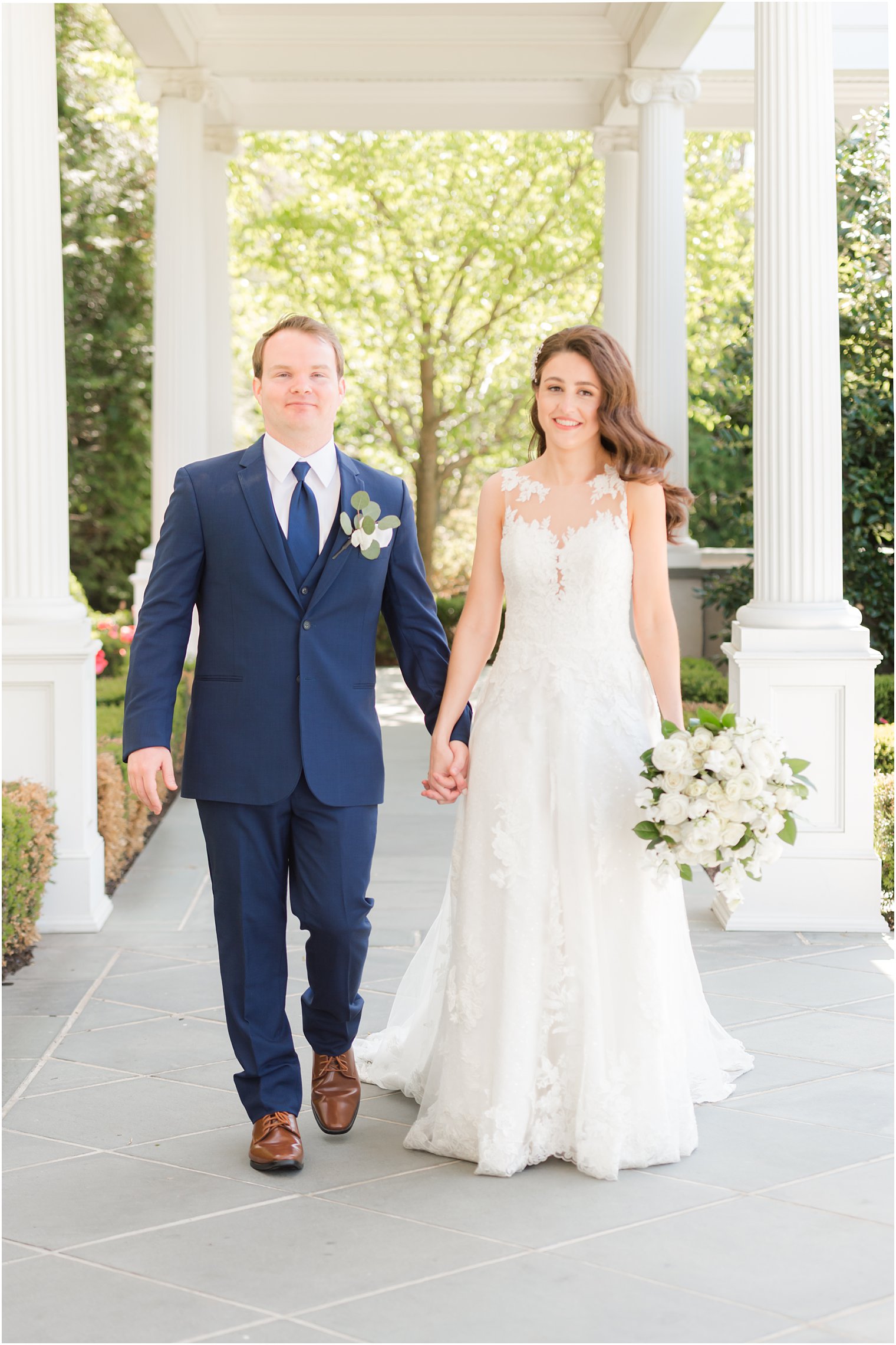 bride and groom hold hands walking through Park Chateau