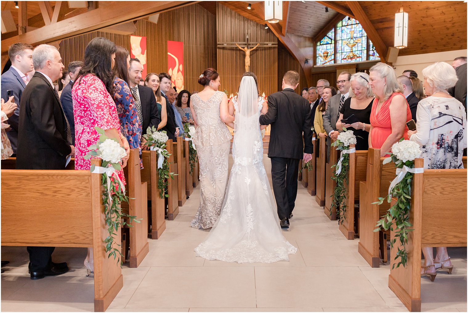 bride walks down aisle with parents for traditional church wedding ceremony in New Jersey