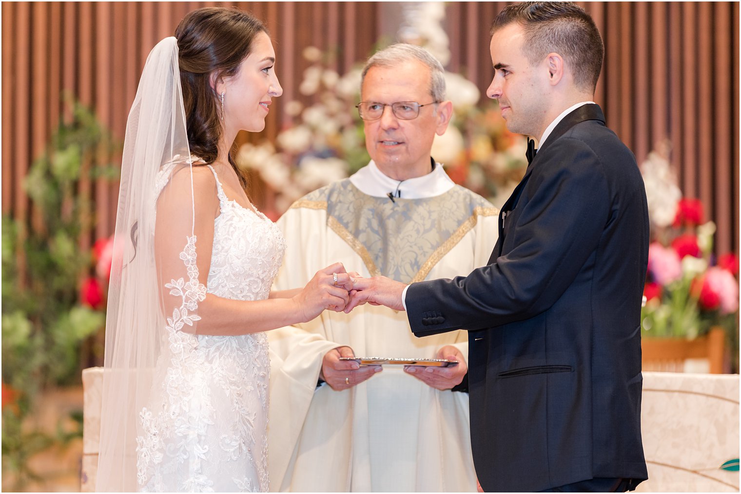 bride puts ring on groom during traditional church wedding ceremony in New Jersey