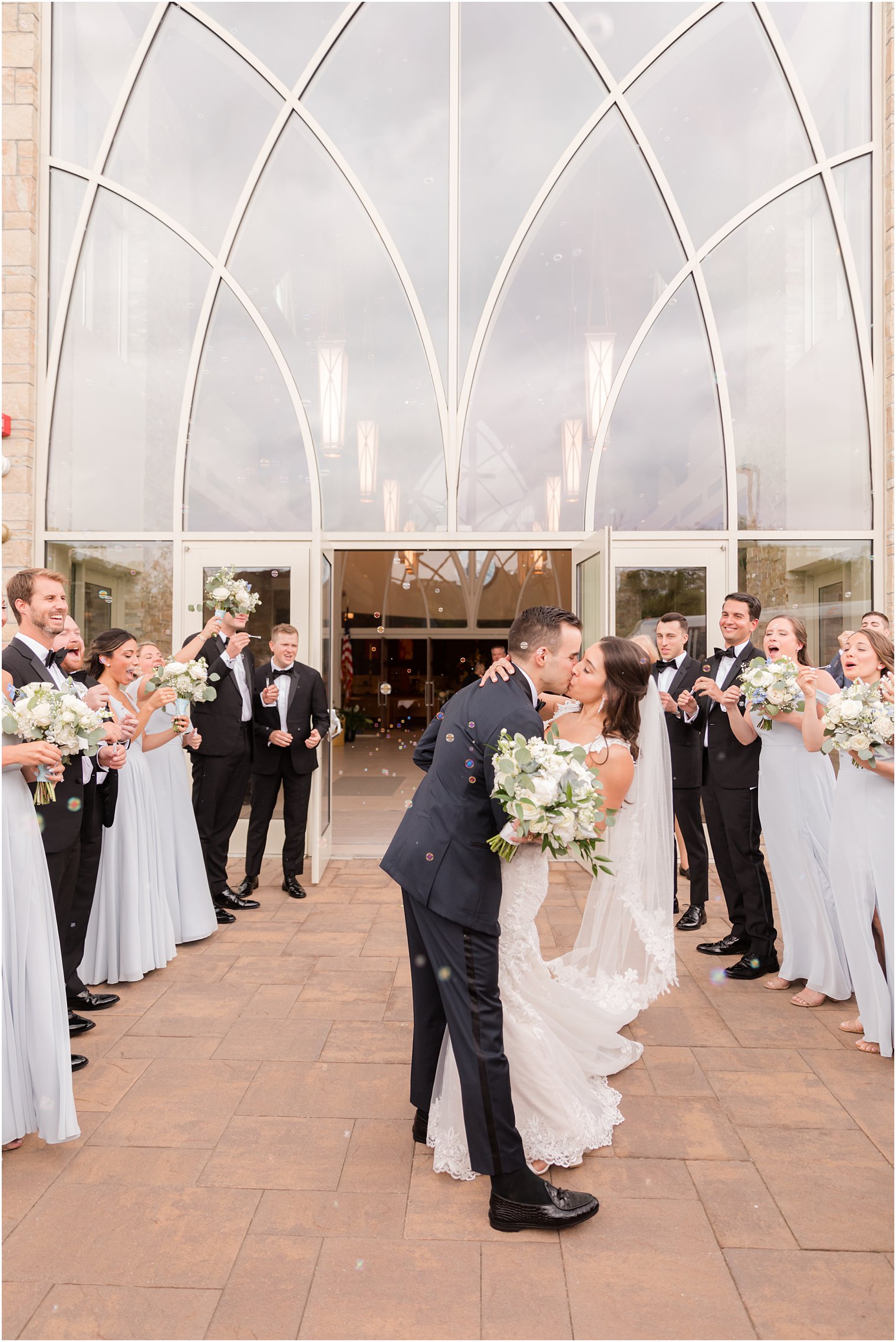 newlyweds kiss outside church while guests clap