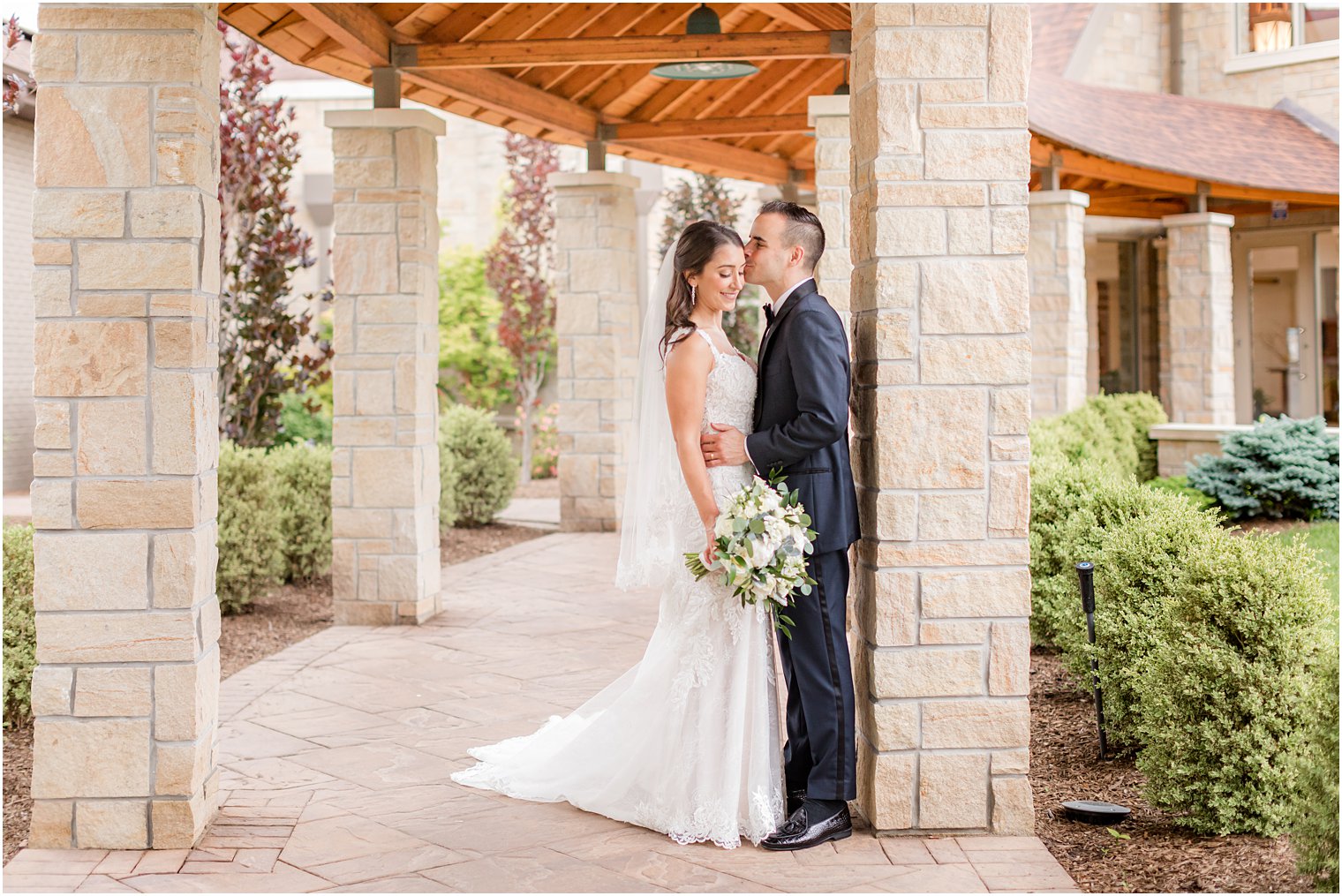 groom hugs bride to him against pillar at NJ church