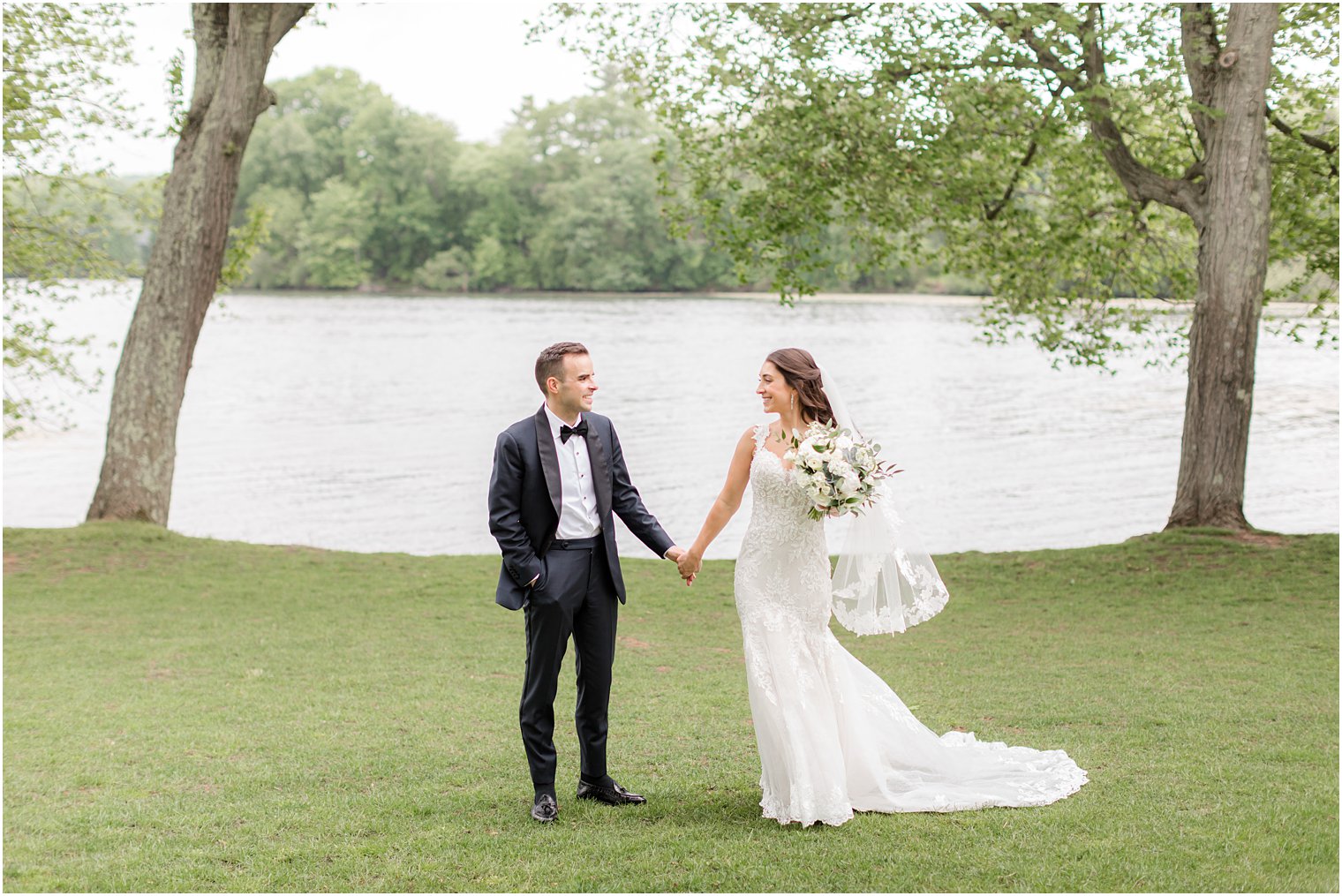 bride and groom hold hands walking by lake at Indian Trail Club