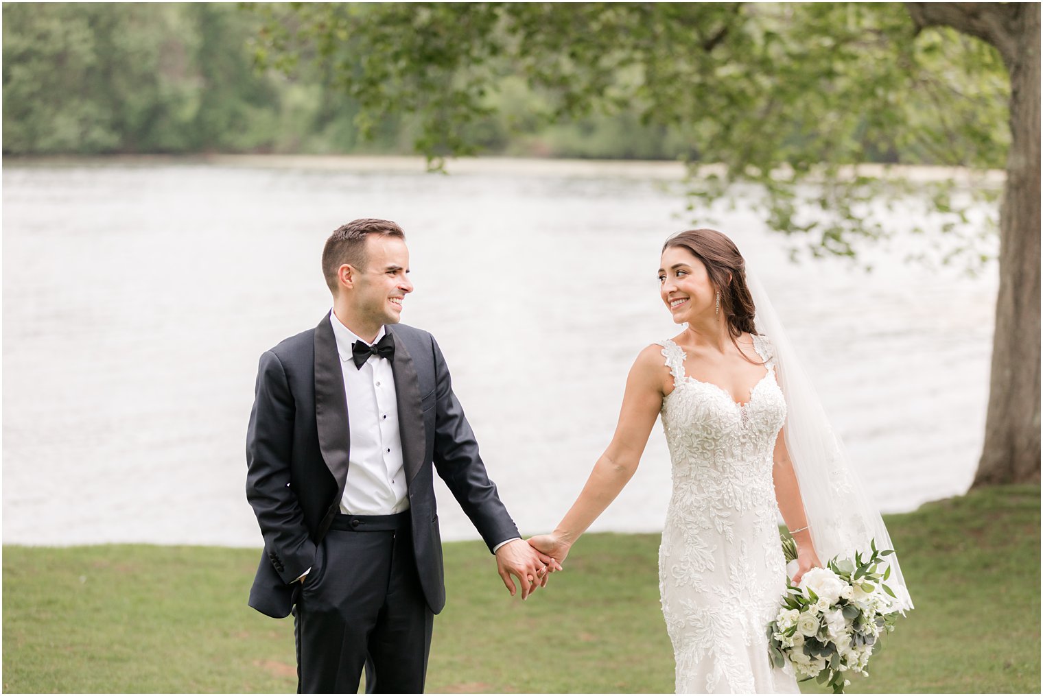 bride and groom hold hands walking along lake at Indian Trail Club
