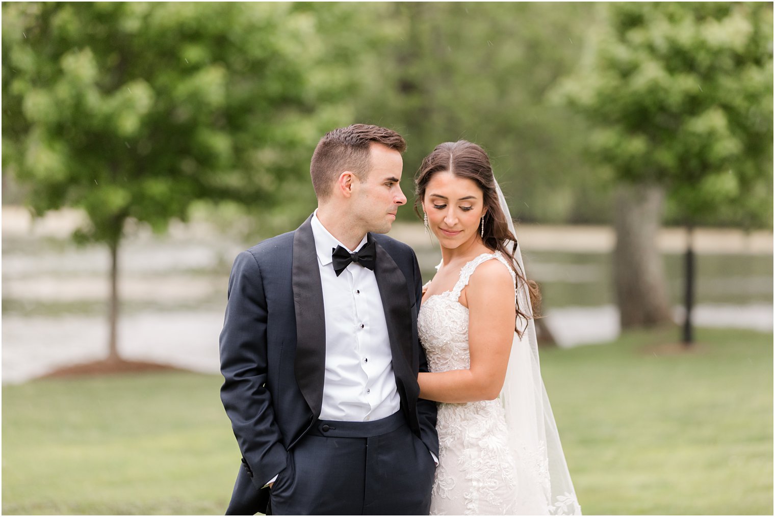 groom looks over at bride who's looking over shoulder during photos at Indian Trail Club