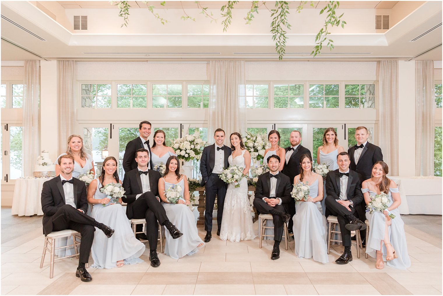 bride and groom sit with wedding party in pale blue and black