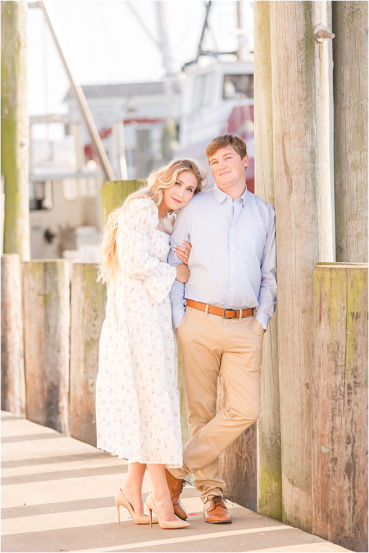 bride leans against groom's arm during Long Beach Island engagement photos on pier