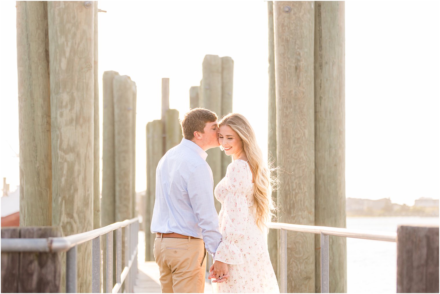 bride and groom lean heads together during photos on wooden pier