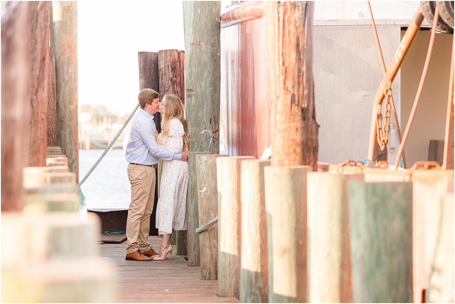 engaged couple leans against wooden pier at Long Beach Island