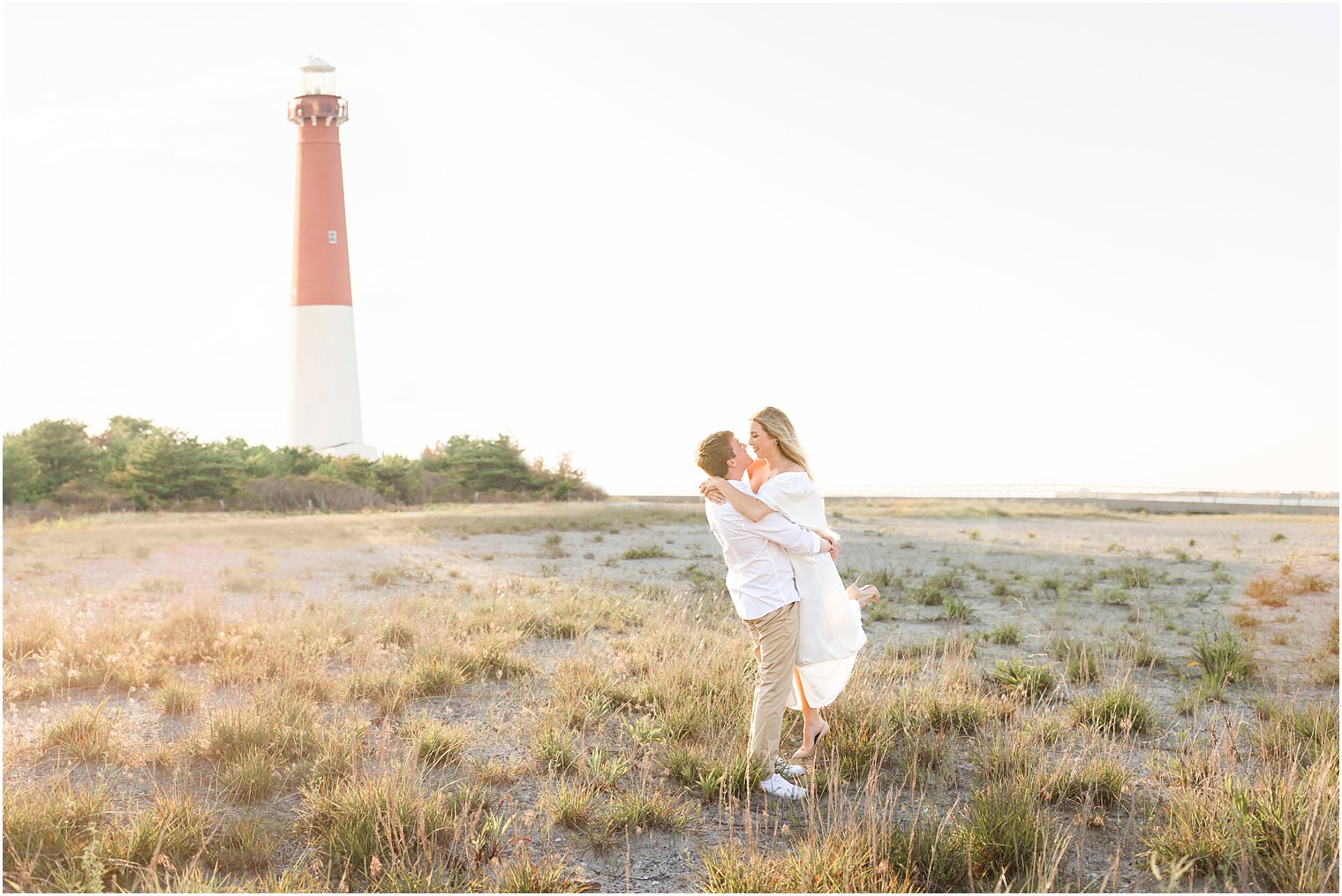 groom lifts bride by lighthouse