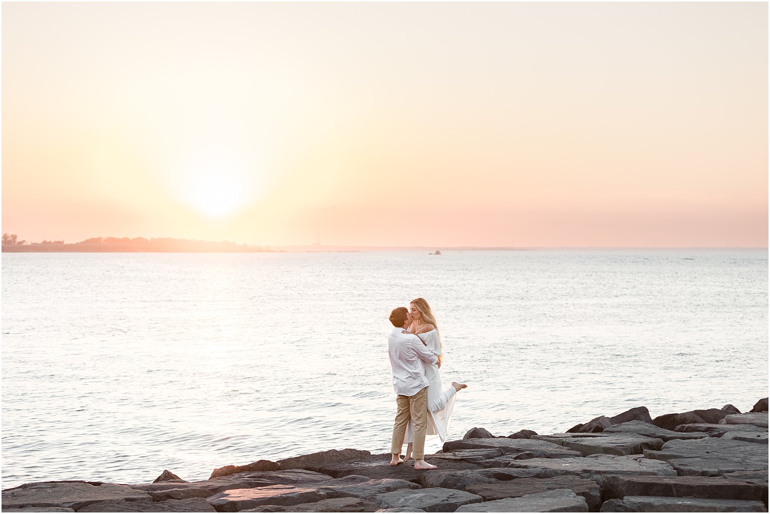 groom lifts bride on rocks at Long Beach Island