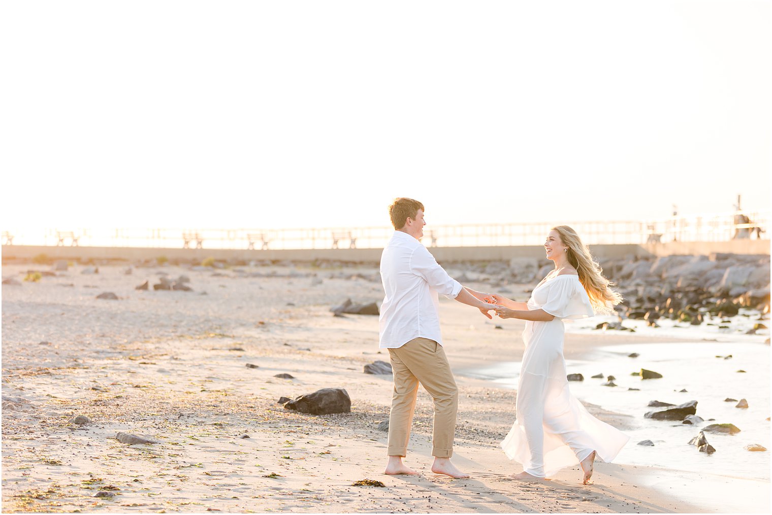 groom twirls bride around on sand at Long Beach Island