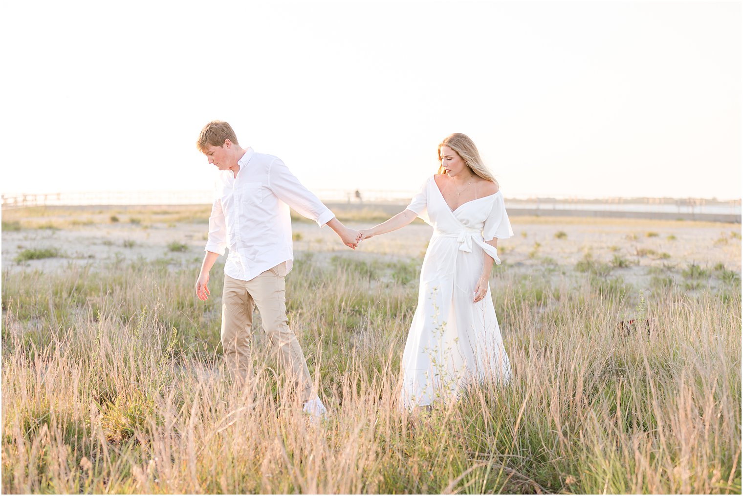 engaged couple walks through grass