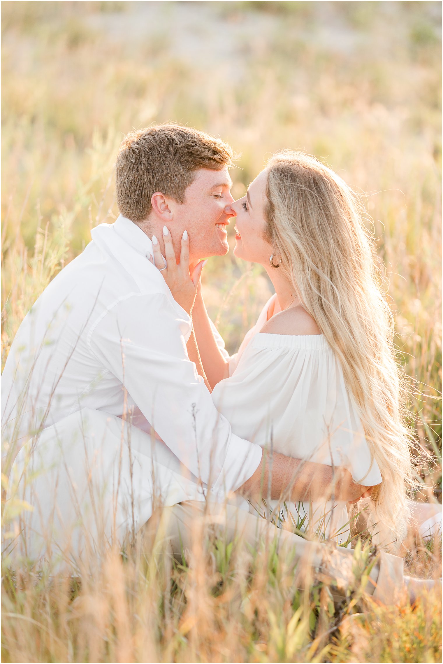 bride and groom kiss at sunset in tall grass 