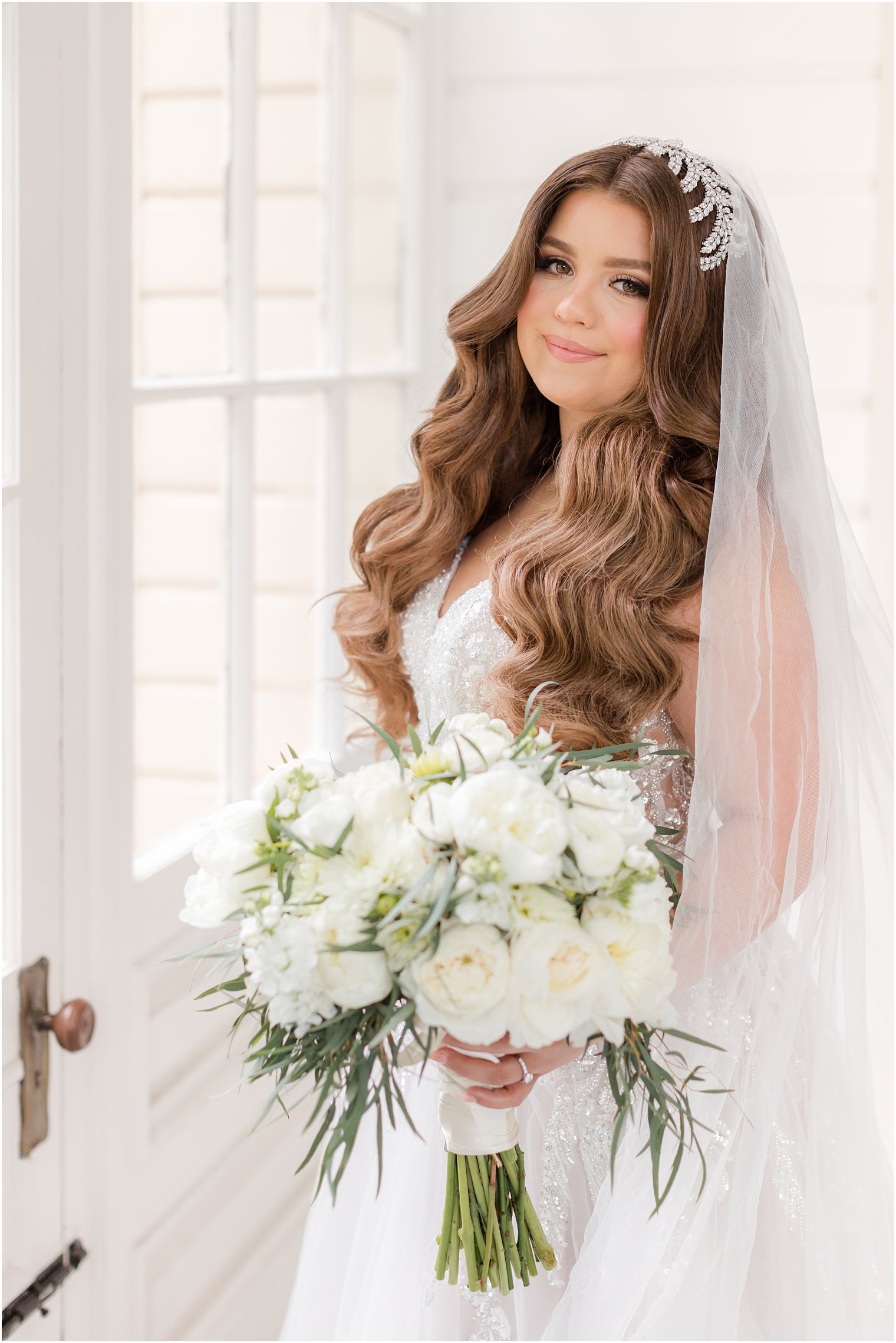 bride smiles looking over shoulder holding bouquet of white flowers at Collingswood Grand Ballroom