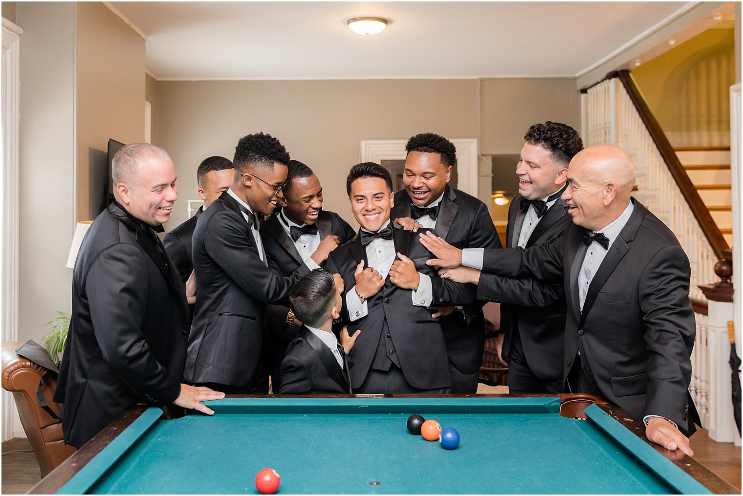 groom and groomsmen hug and goof off by pool table at Collingswood Grand Ballroom