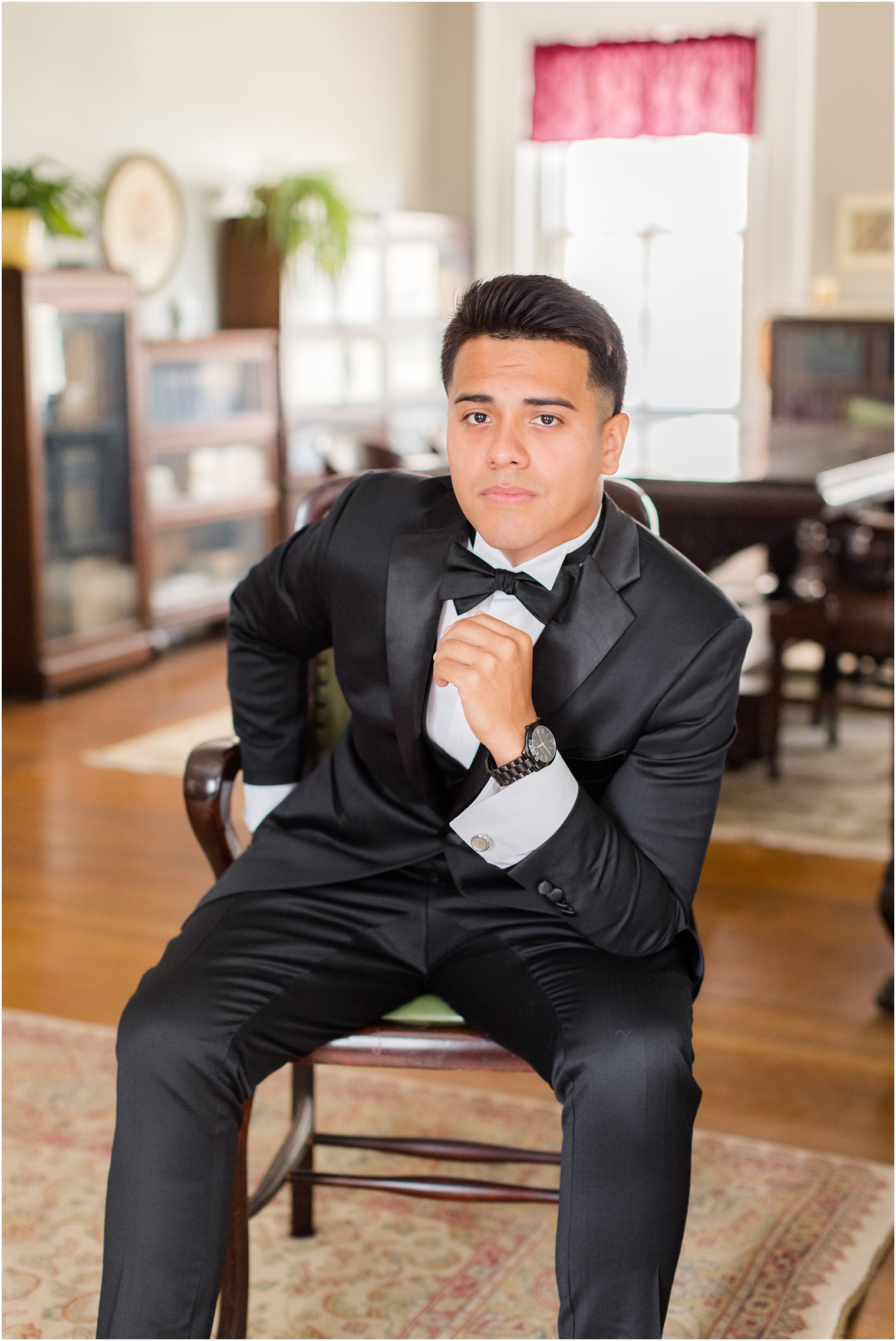 groom leans on knee in black suit at Collingswood Grand Ballroom