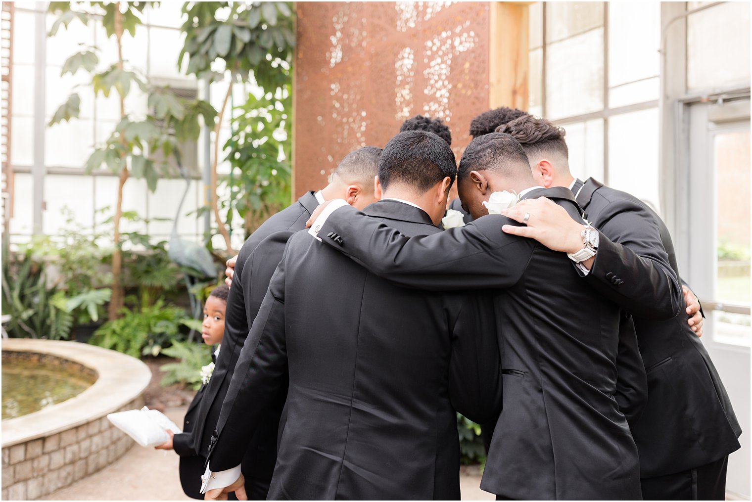 groomsmen huddle around groom before Fairmont Park Horticulture Center wedding ceremony