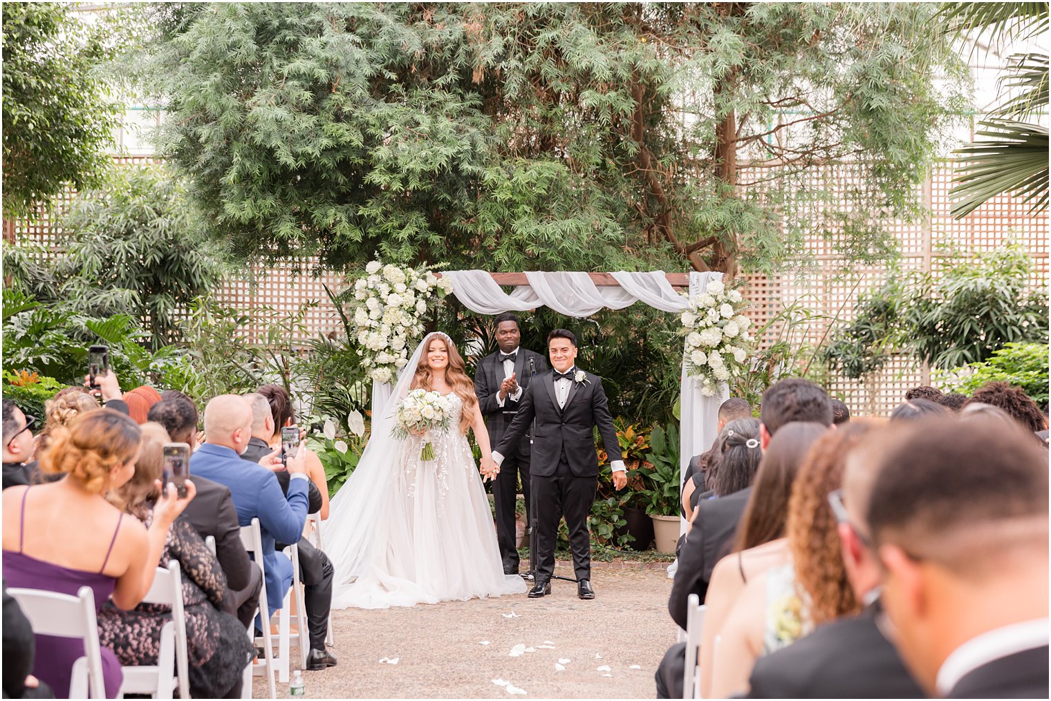couple turns to walk up aisle at Fairmont Park Horticulture Center wedding in greenhouse