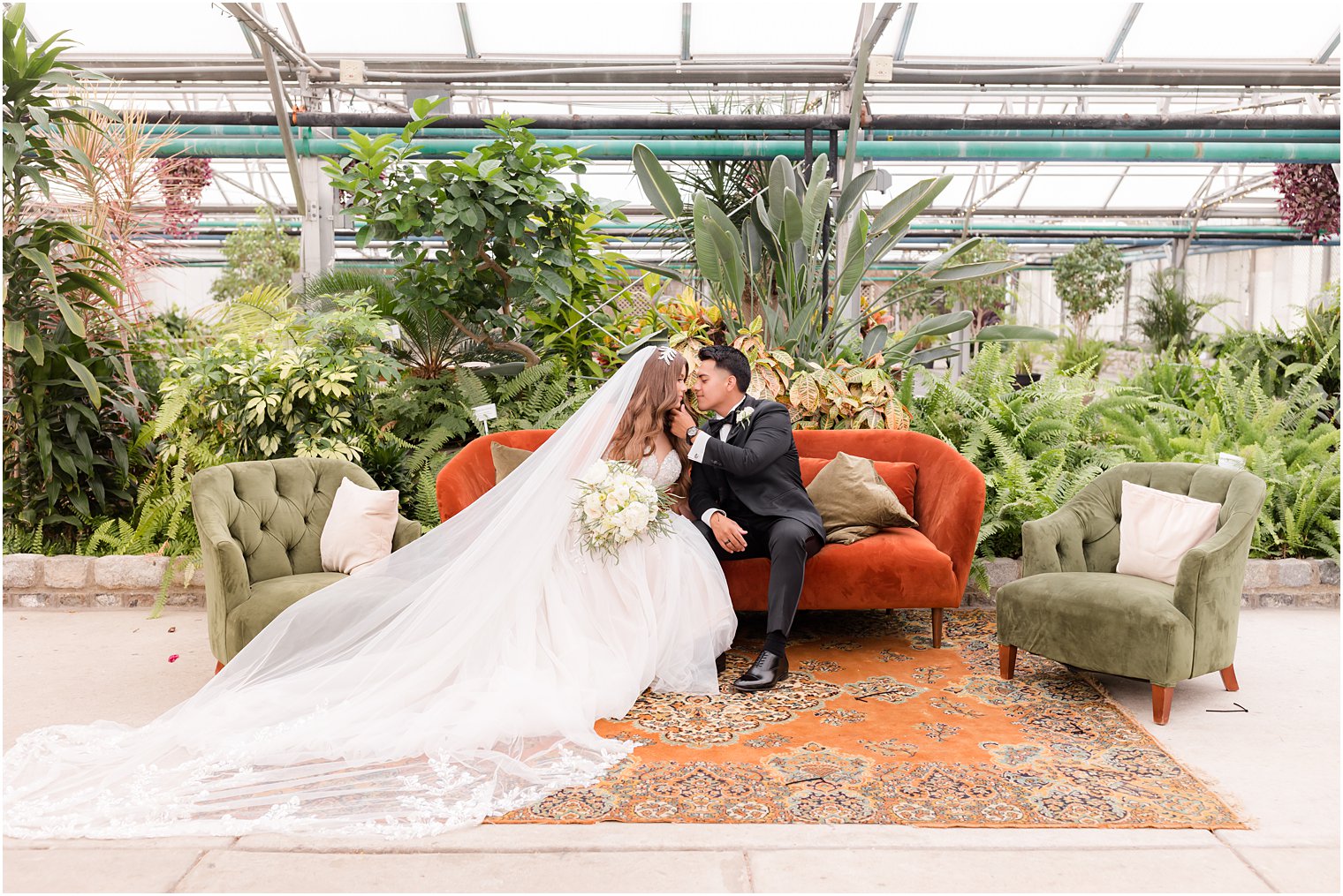 bride and groom sit on sofa inside greenhouse at Fairmont Park Horticulture Center 