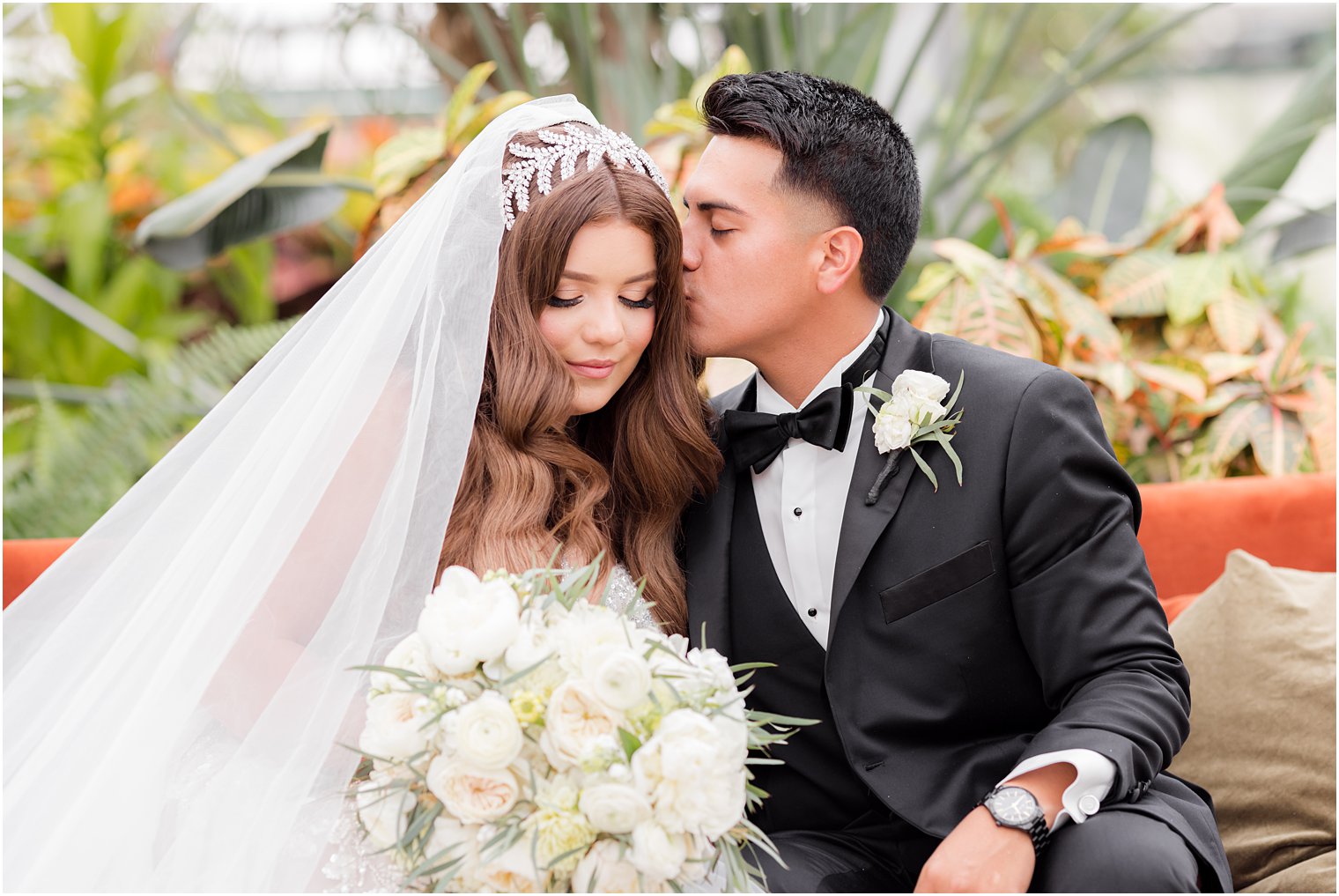 groom kisses bride's forehead during Fairmont Park Horticulture Center wedding portraits 