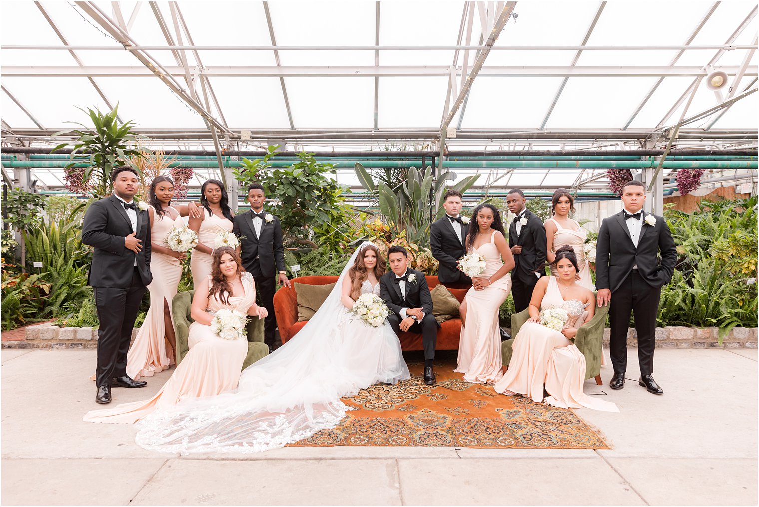 bride and groom pose with wedding party in black suits and pink gowns at Fairmont Park Horticulture Center