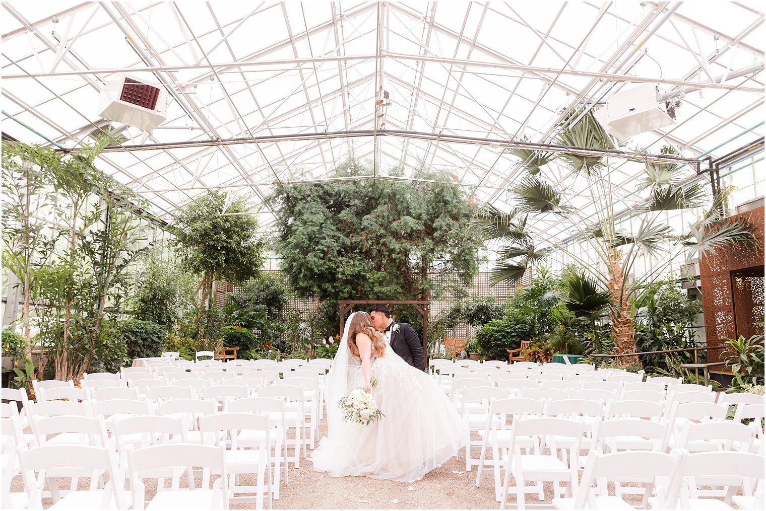 newlyweds kiss in greenhouse at Fairmont Park Horticulture Center 