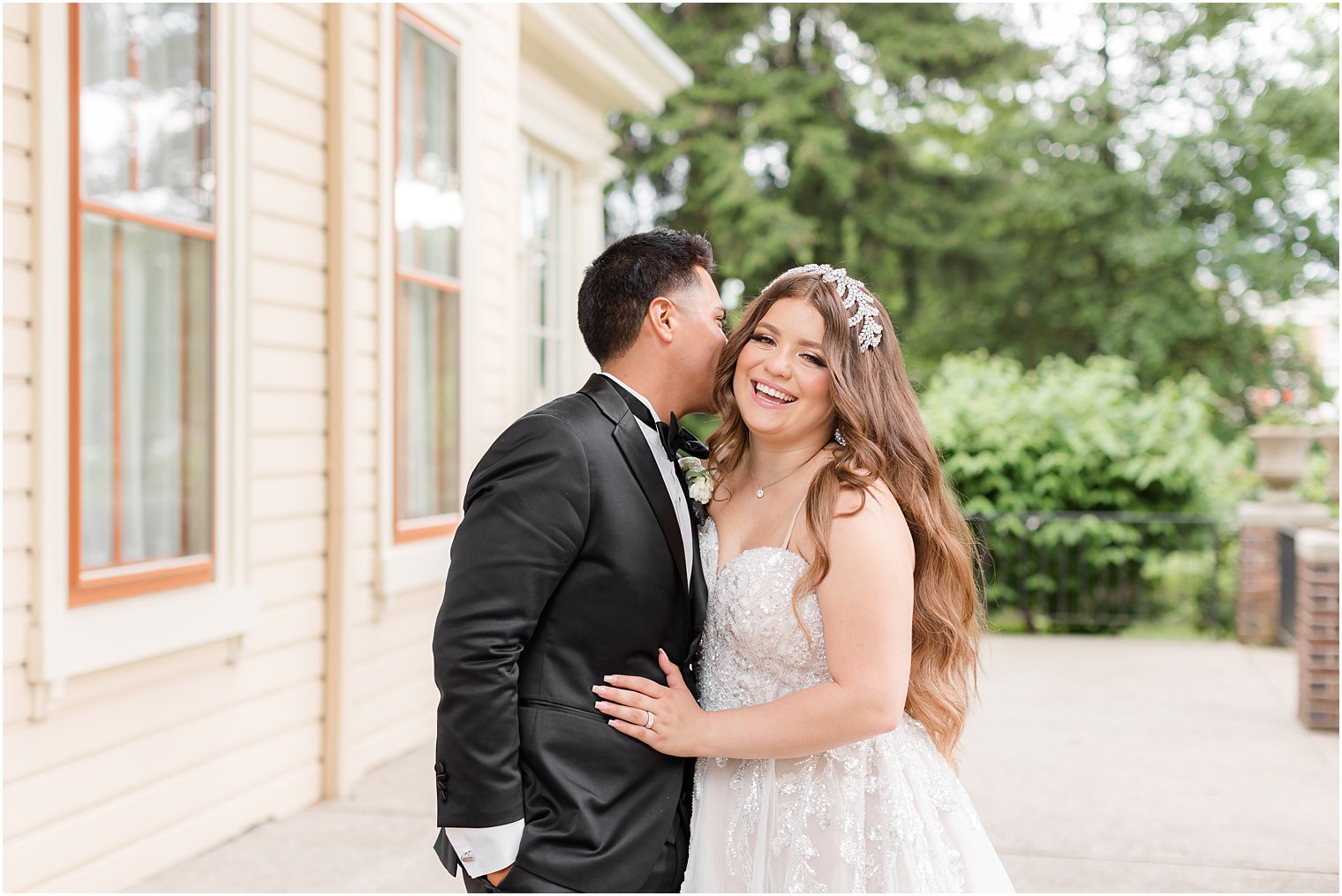 groom leans to kiss bride's cheek during portraits at Fairmount Park