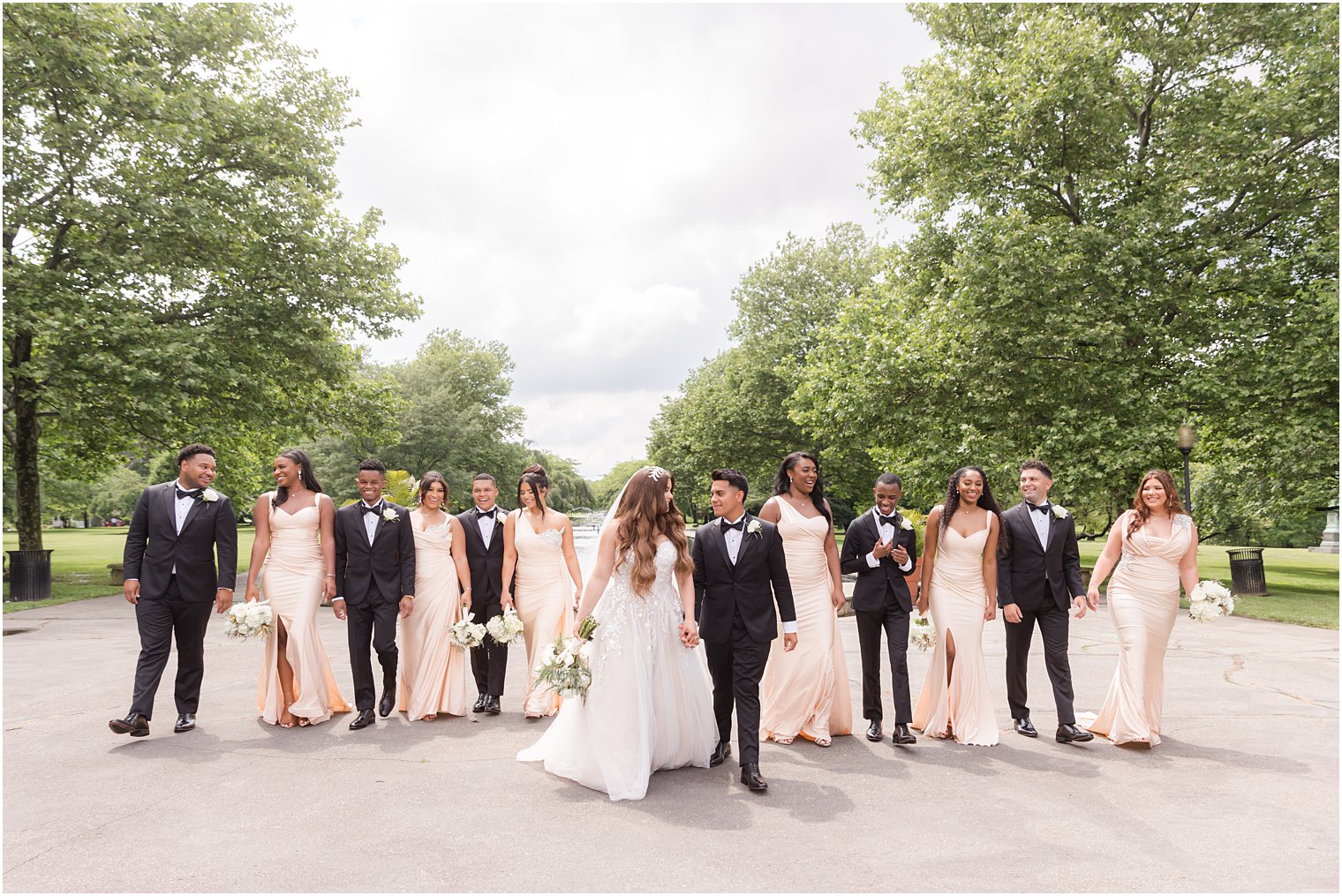 newlyweds walk with wedding party behind them in Philadelphia PA park