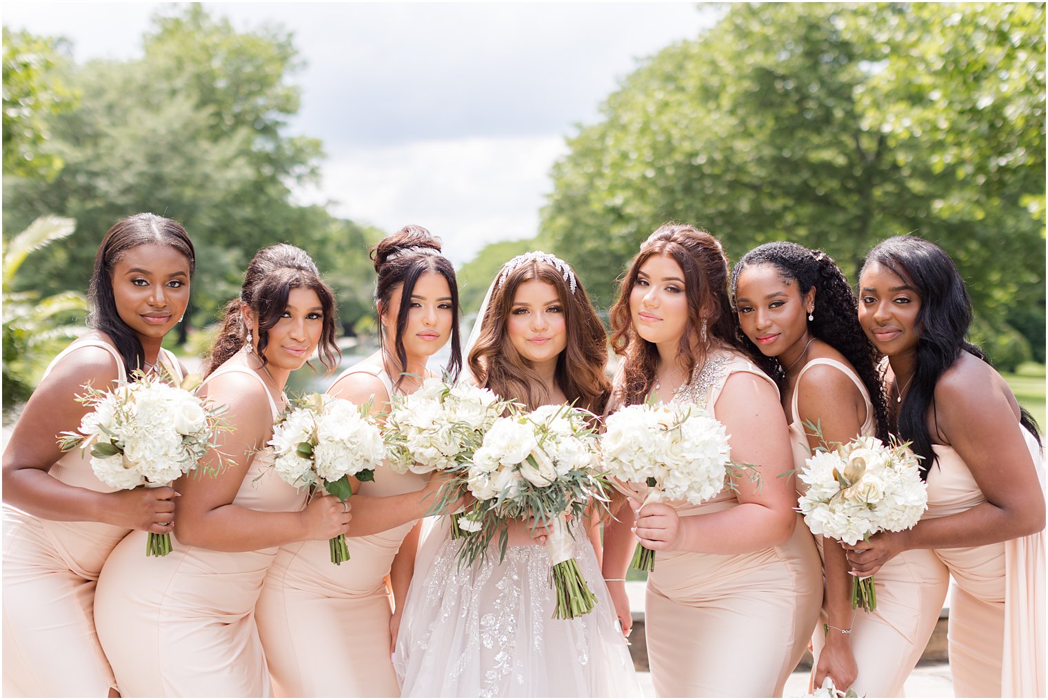 bride poses with bridesmaids in pink gowns with white bouquets 