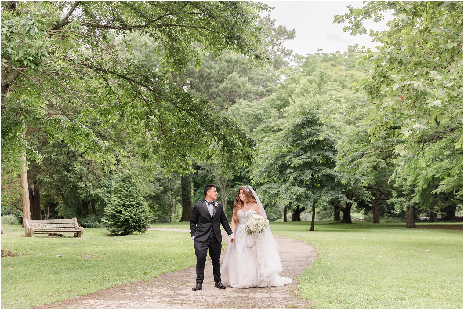 bride and groom hold hands walking through Fairmount Park Horticulture Center