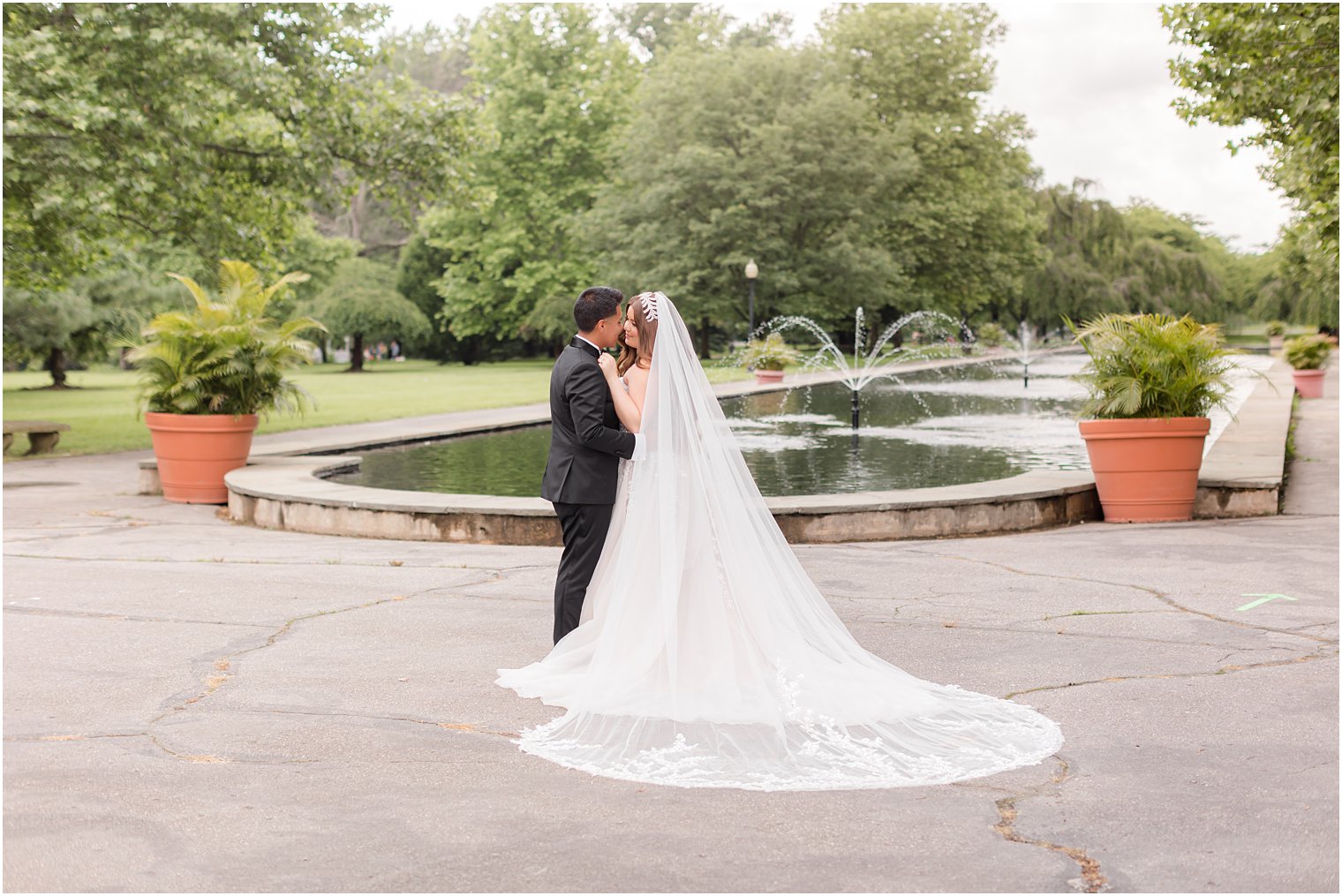 bride and groom pose by fountain at Fairmount Park Horticulture Center