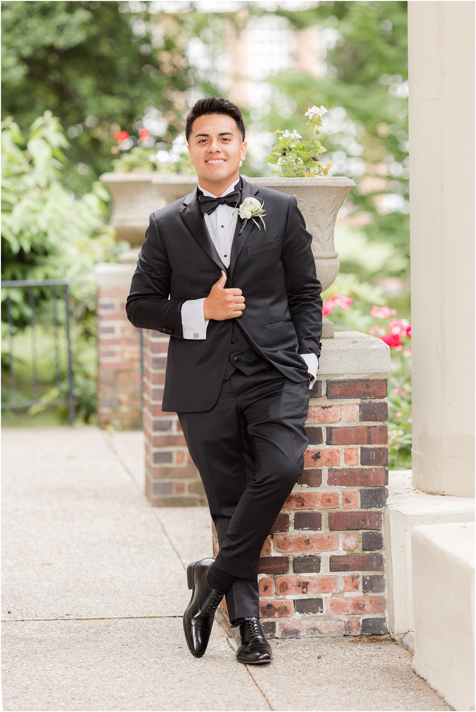 groom leans against brick column outside Collingswood Grand Ballroom 