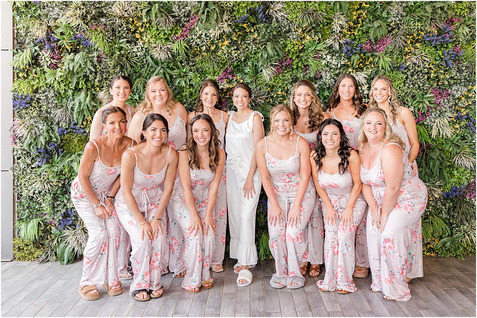 bride and bridesmaids pose by greenery wall at Ryland Inn