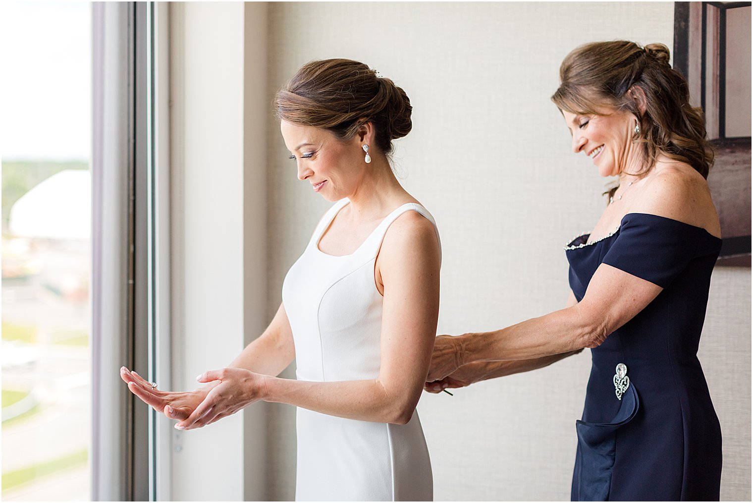 mother helps bride into wedding gown before Ryland Inn wedding