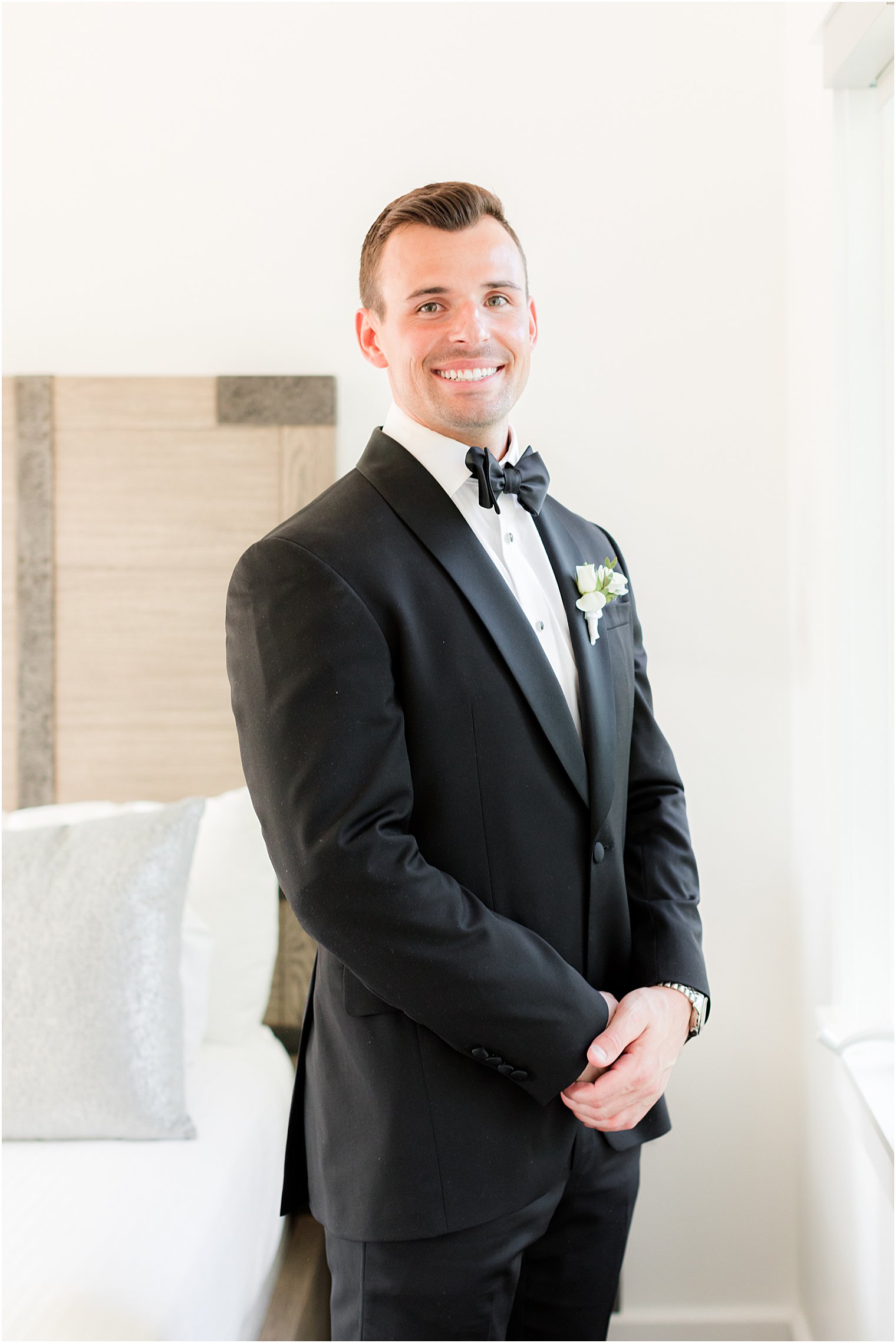 groom stands in classic tux with hands over his jacket