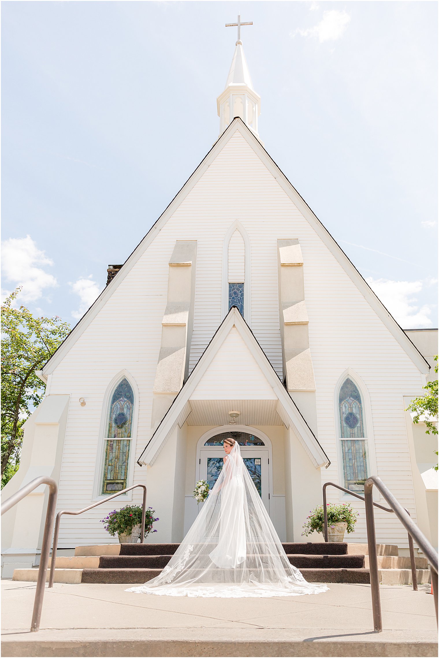 bride stands outside St. Joseph Roman Catholic Church with veil draped behind her